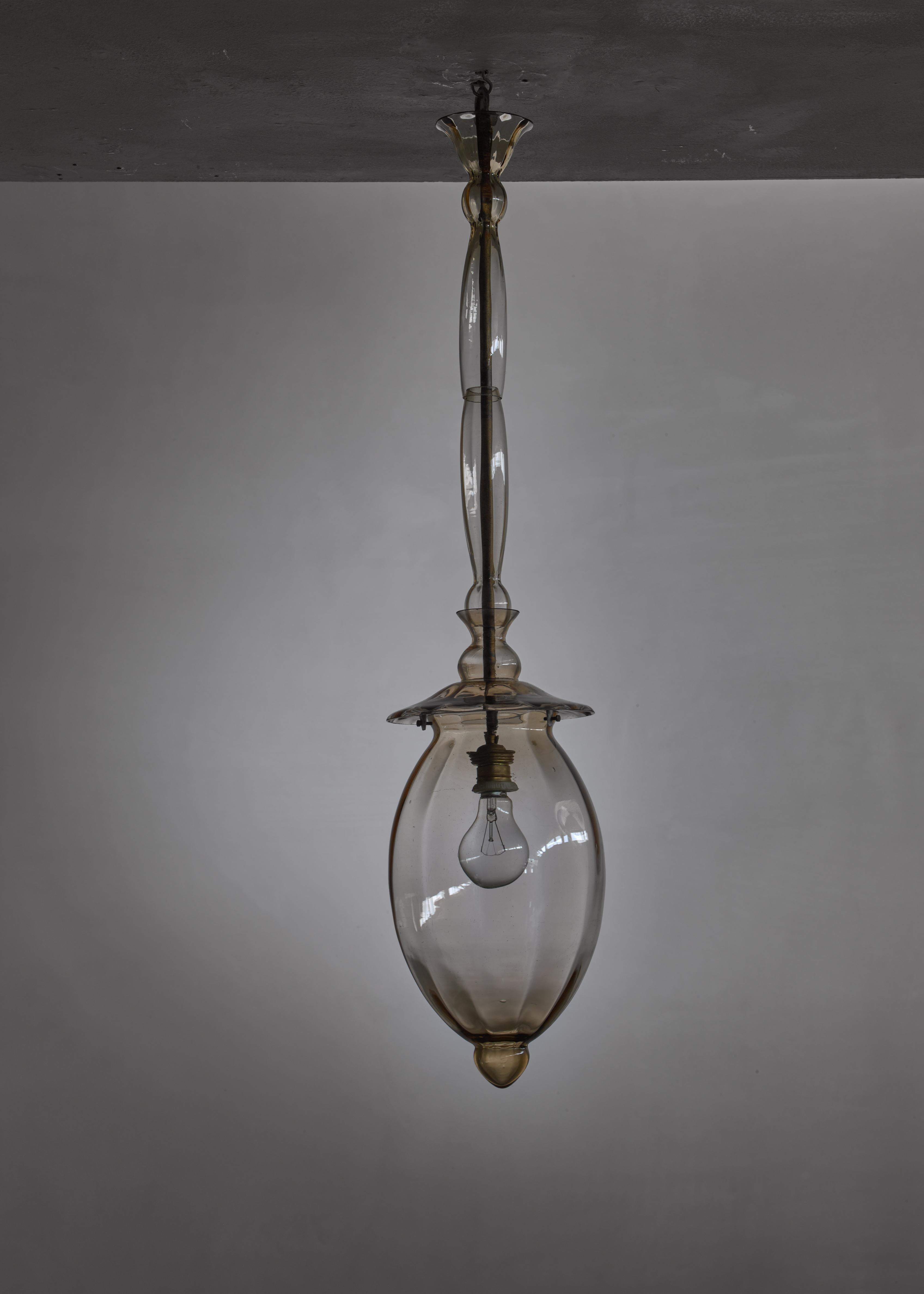A taupe Murano glass 'Doge' type pendant lamp from Italy. The lamp is made of four glass elements in transparent amber around a brass stem.

Marked with the etched Murano coat of arms.