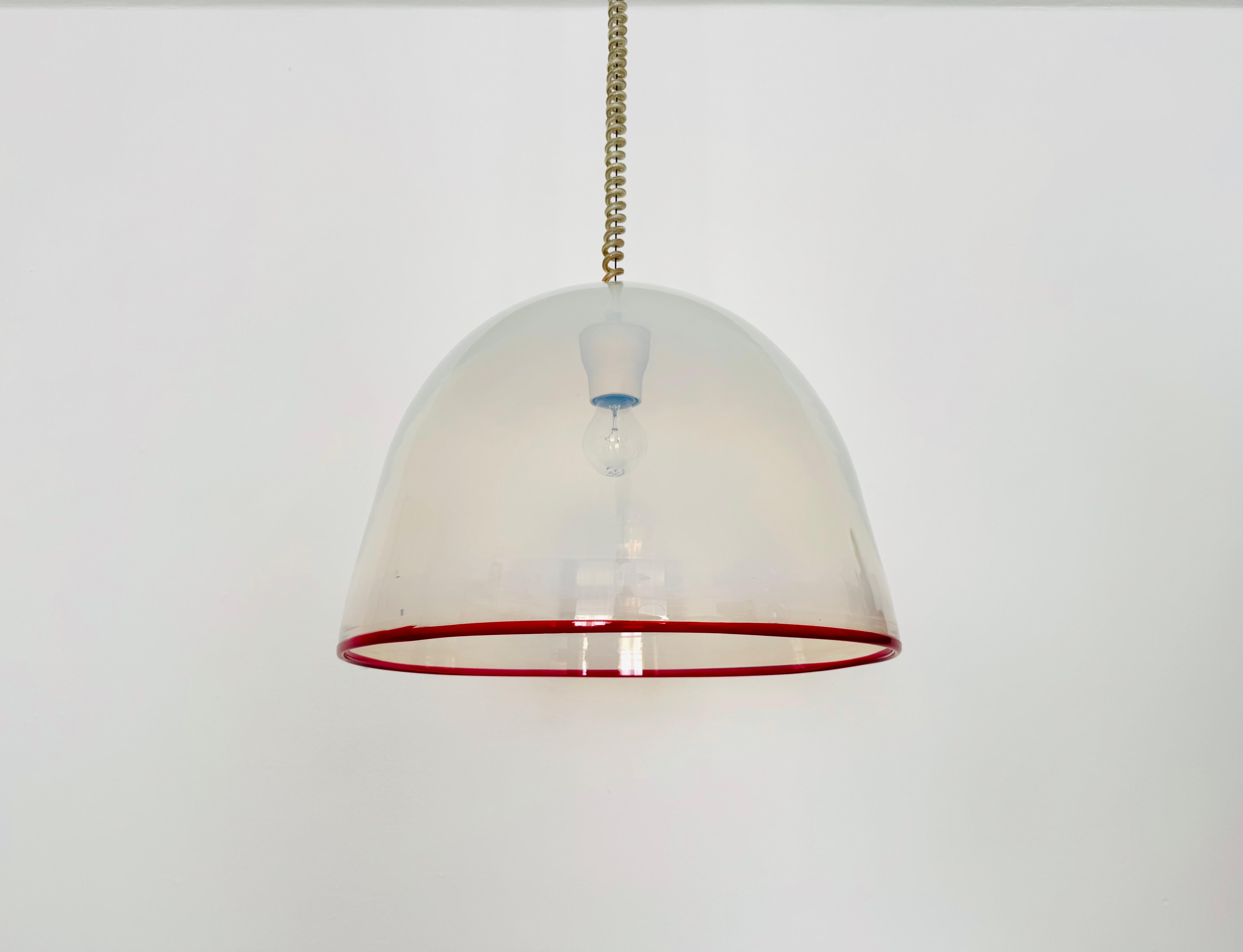 Impressionnante lampe en verre de Murano datant des années 1960.
Une conception exceptionnellement réussie et une réalisation de très haute qualité.
Le verre spécial et le bord rouge décoratif créent une lumière spectaculaire.

Design/One : Roberto
