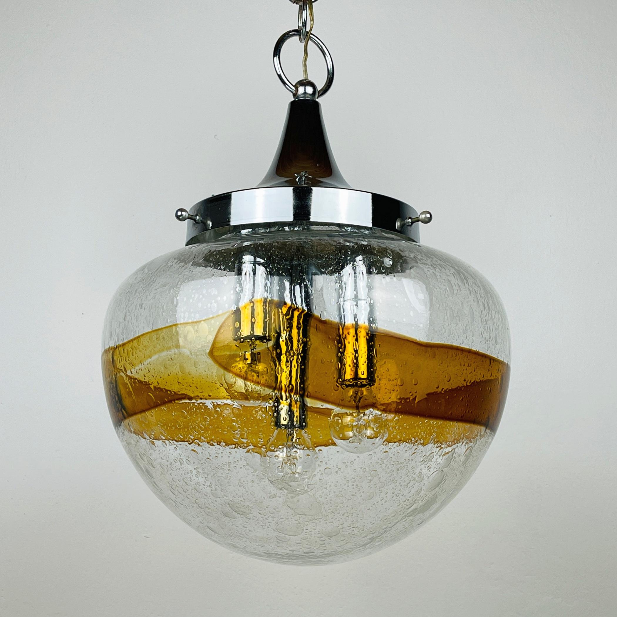 L'exquise lampe suspendue en verre de Murano soufflé à la main, provenant de l'Italie des années 1970. Ce chef-d'œuvre met en valeur un abat-jour en verre transparent orné d'un captivant traitement 