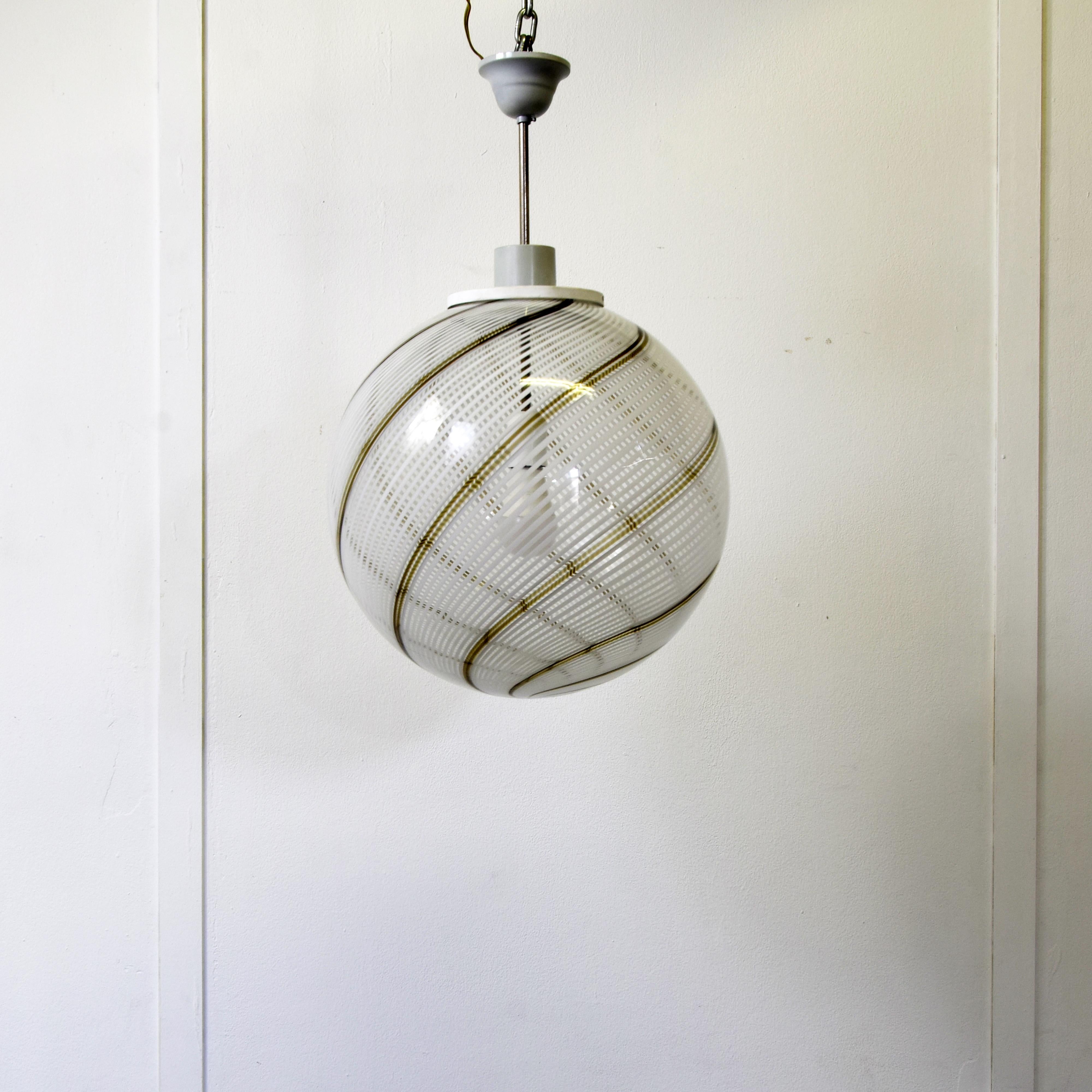 This pendant lamp Vennini att. is distinguished by its elegant spherical shape and refined craftsmanship in Murano glass, executed according to the ancient techniques of Venetian master glassmakers. The glass is embellished with a twisted filigree,