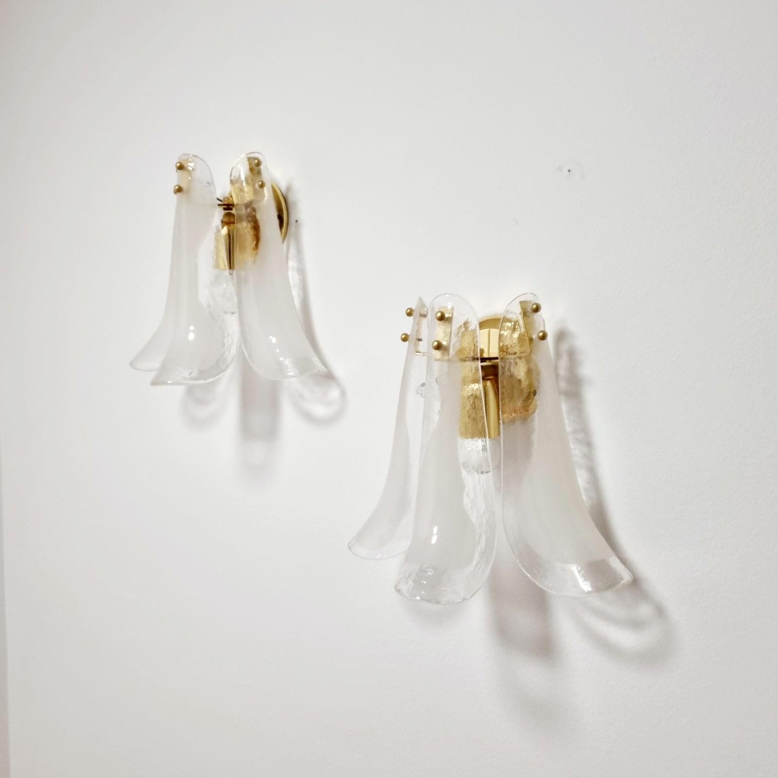 Pair of beautiful Murano glass wall sconces. Made of 3 petal shaped white and clear glass shades and brass structure.
Designed by Carlo Nason and produce by Mazzega
In very good condition, working perfectly.

Available 5 sets of wall lamps.