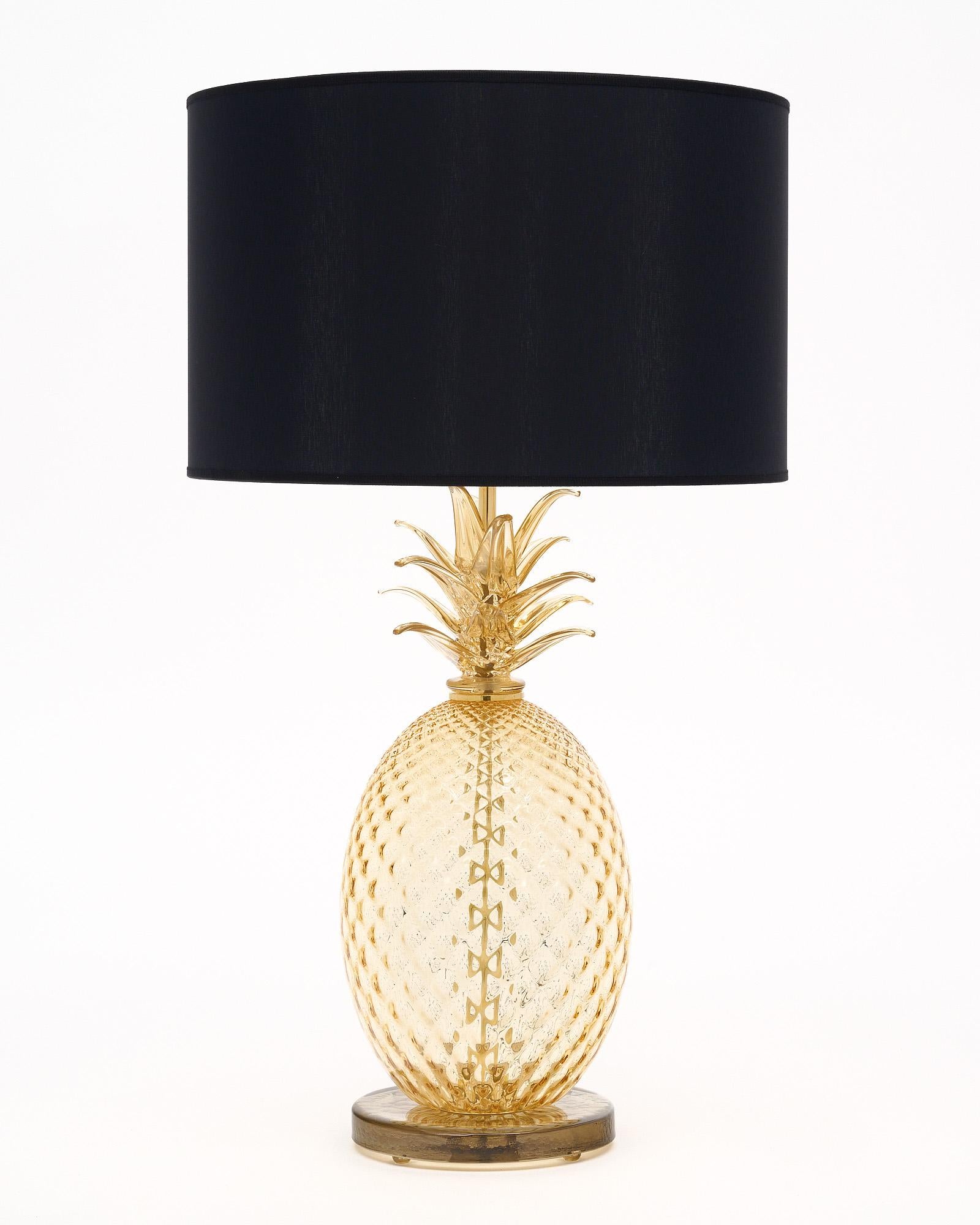 Pair of lamps made of hand-blown glass from Murano, Italy. Each lamp depicts a pineapple – known as an international gesture of hospitality. The glass is a warm and inviting golden tone. They have been newly wired to fit US standards.