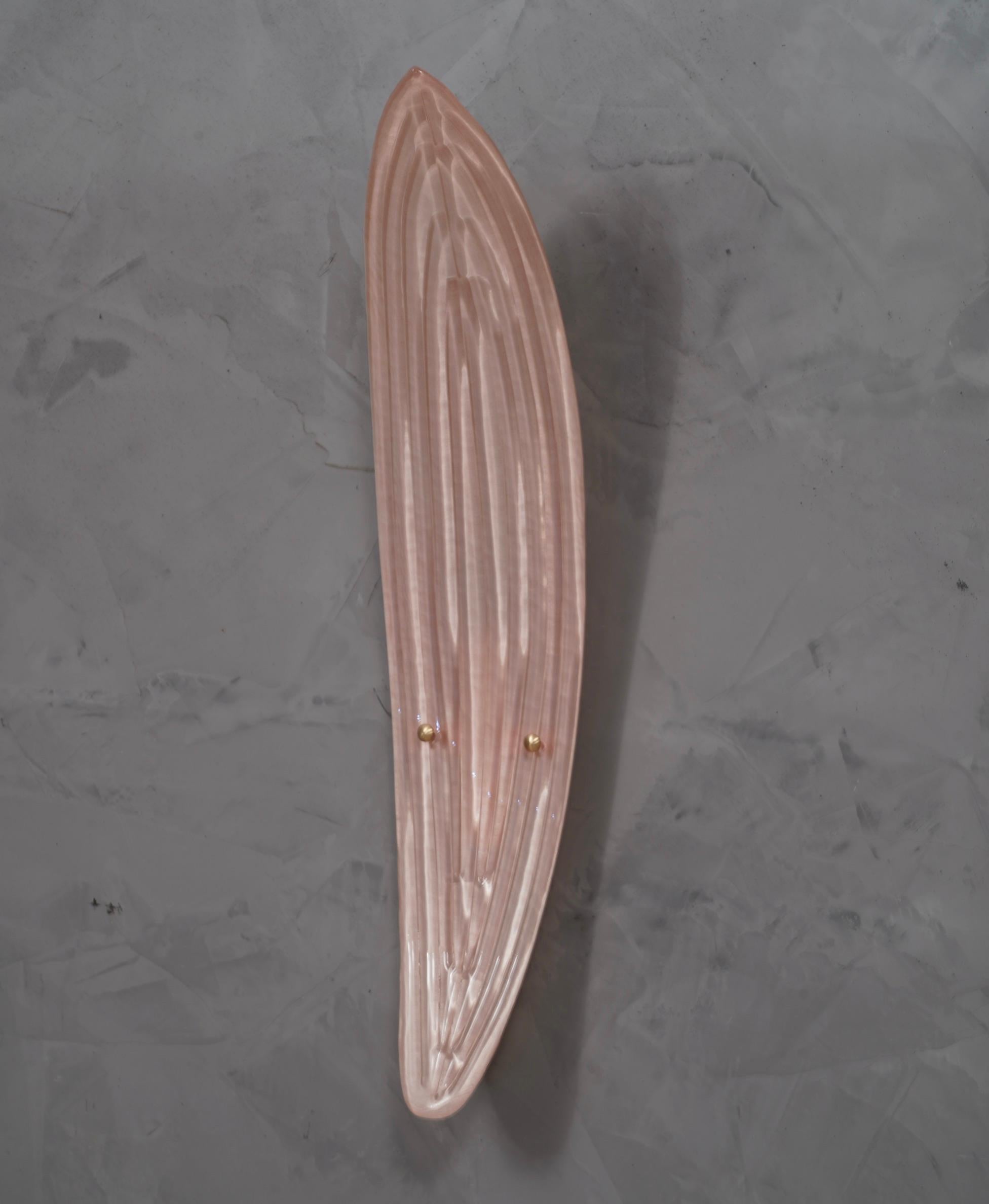 Precioso diseño para este aplique en forma de hoja, todo rosa con una serie de una nervadura vertical. Hoja estilizada muy extensa, una obra maestra artística de Murano.

El aplique consiste en una estructura trasera de metal pintado de blanco donde