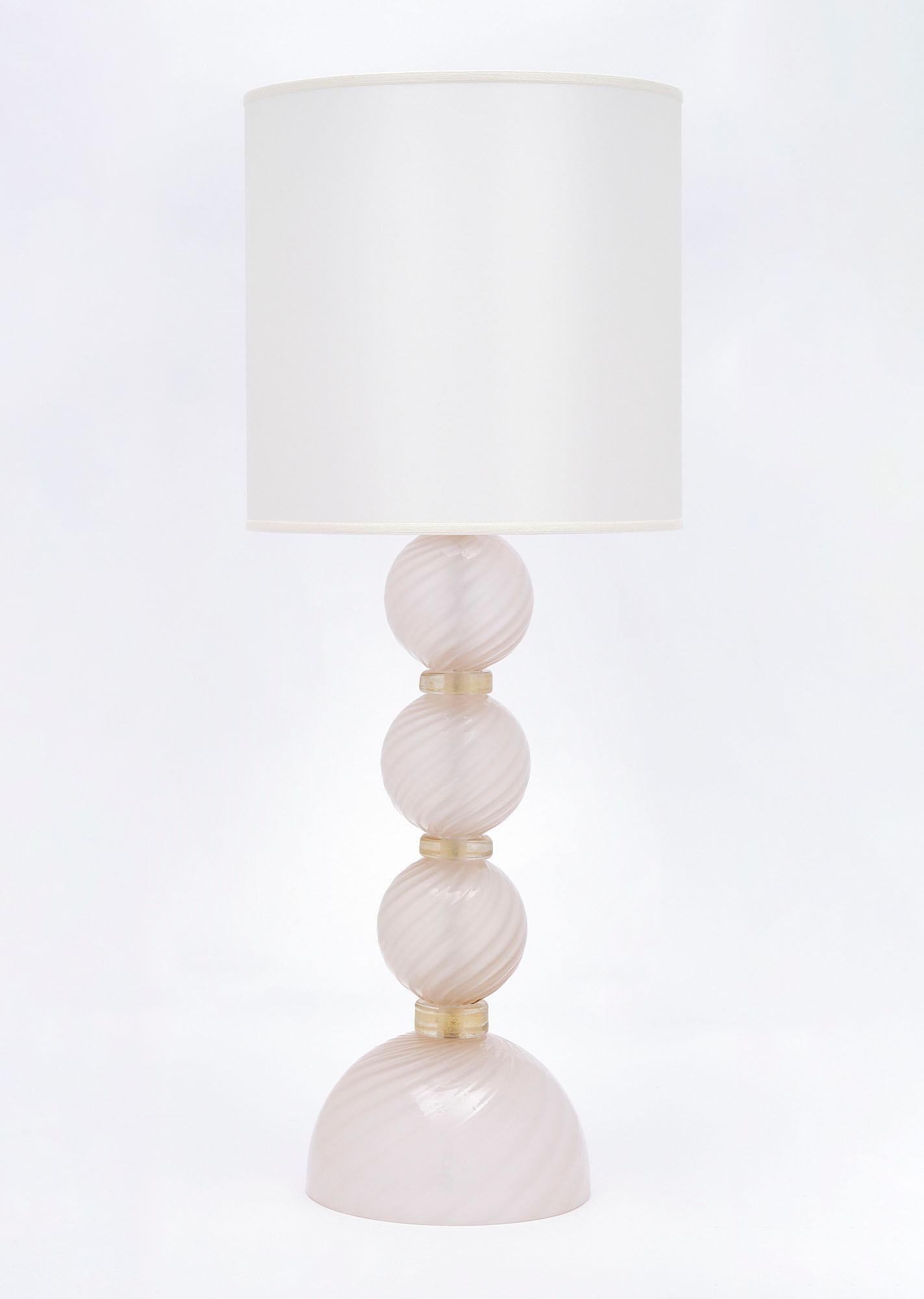 Pair of lamps of Murano glass from Italy. These lamps feature spheres of swirling hand-blown glass on a glass base in a beautiful light pink tone. Each sphere is separated with a 24 carat gold fused ring of glass. They have been newly wired to fit