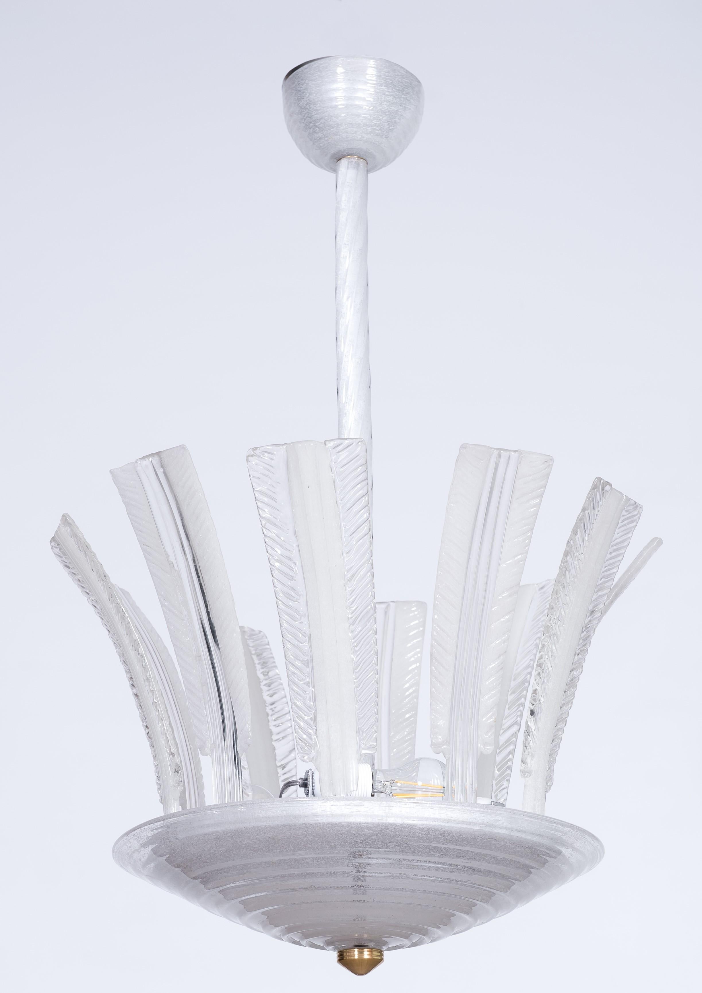Lustre Puligoso en verre de Murano avec feuilles de palmier attribué à Barovier 1950s.
Dix feuilles de palmier en verre penchées vers l'extérieur sont placées sur la base centrale en verre et entourent les trois lumières centrales.
Le diamètre