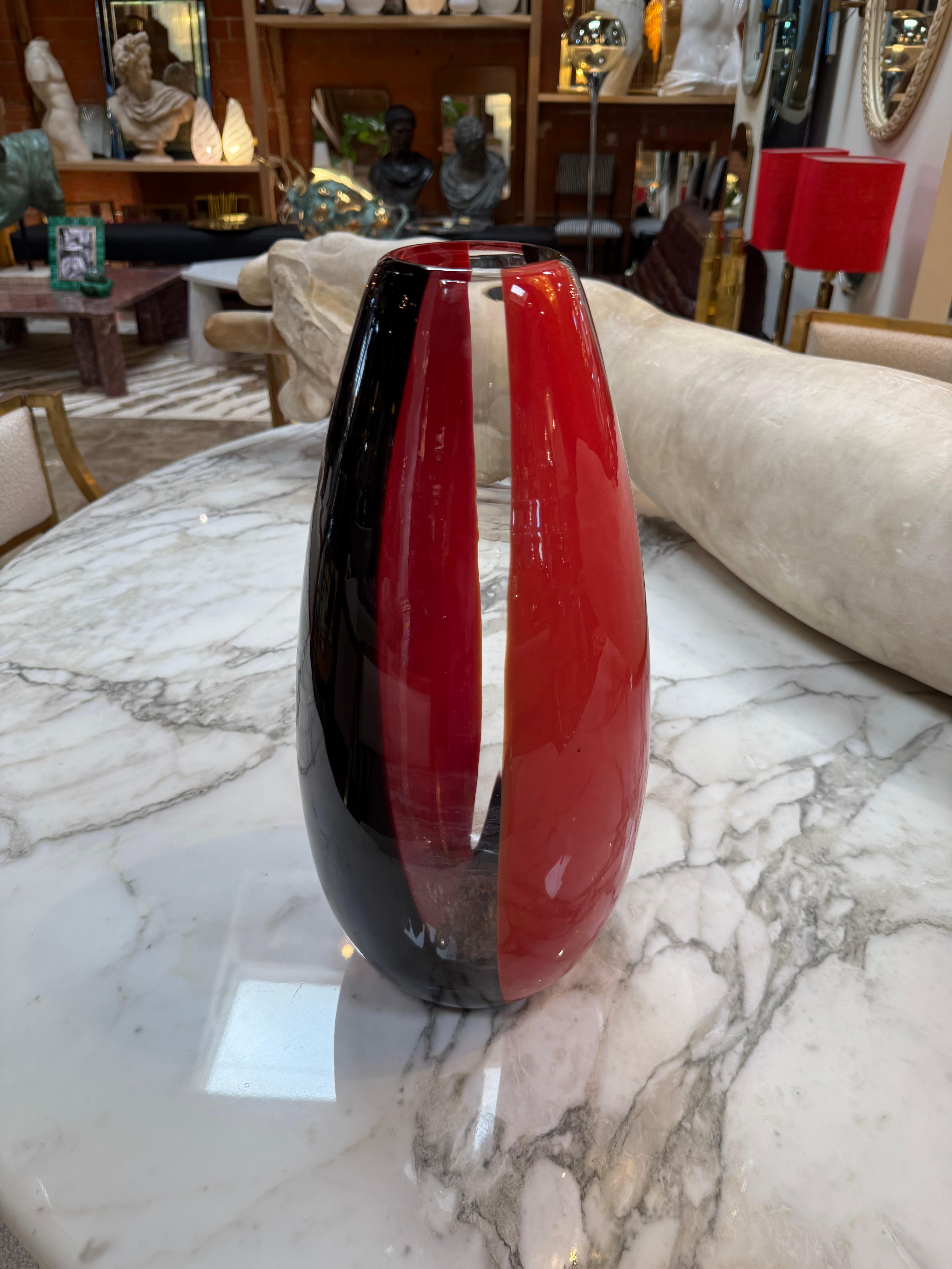 Vase étonnant en verre de Murano présentant des bandes verticales rouges et noires audacieuses avec une finition très brillante. Soufflée à la main par des artisans vénitiens, cette pièce met en valeur la clarté et le savoir-faire exceptionnels de