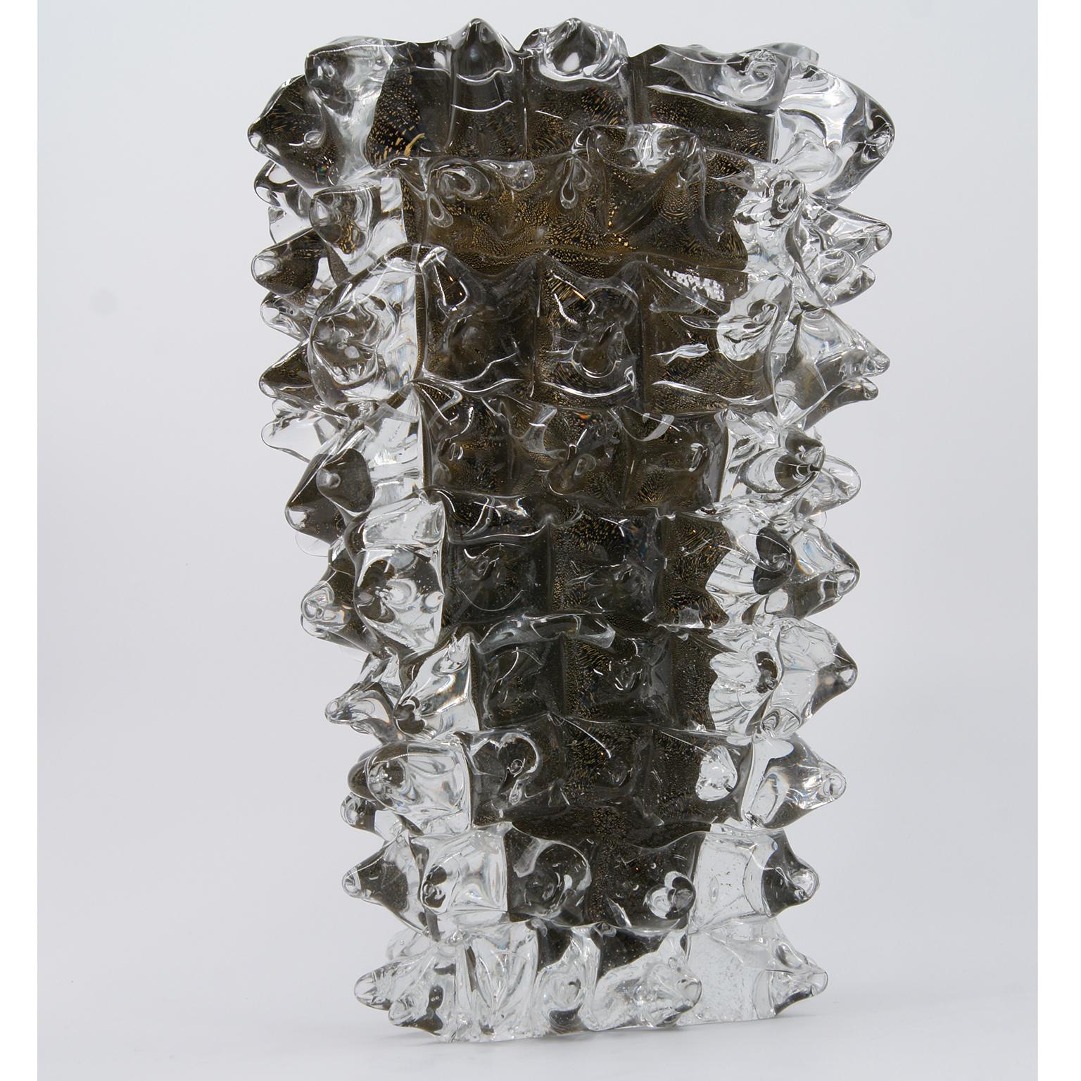 Voici un étonnant vase à l'âme dorée, méticuleusement fabriqué à la main par Roberto Beltrami et son équipe qualifiée à Murano.

Ces vases majestueux sont façonnés avant d'être ornés de pointes de verre transparent brûlant fusionnées tout autour.