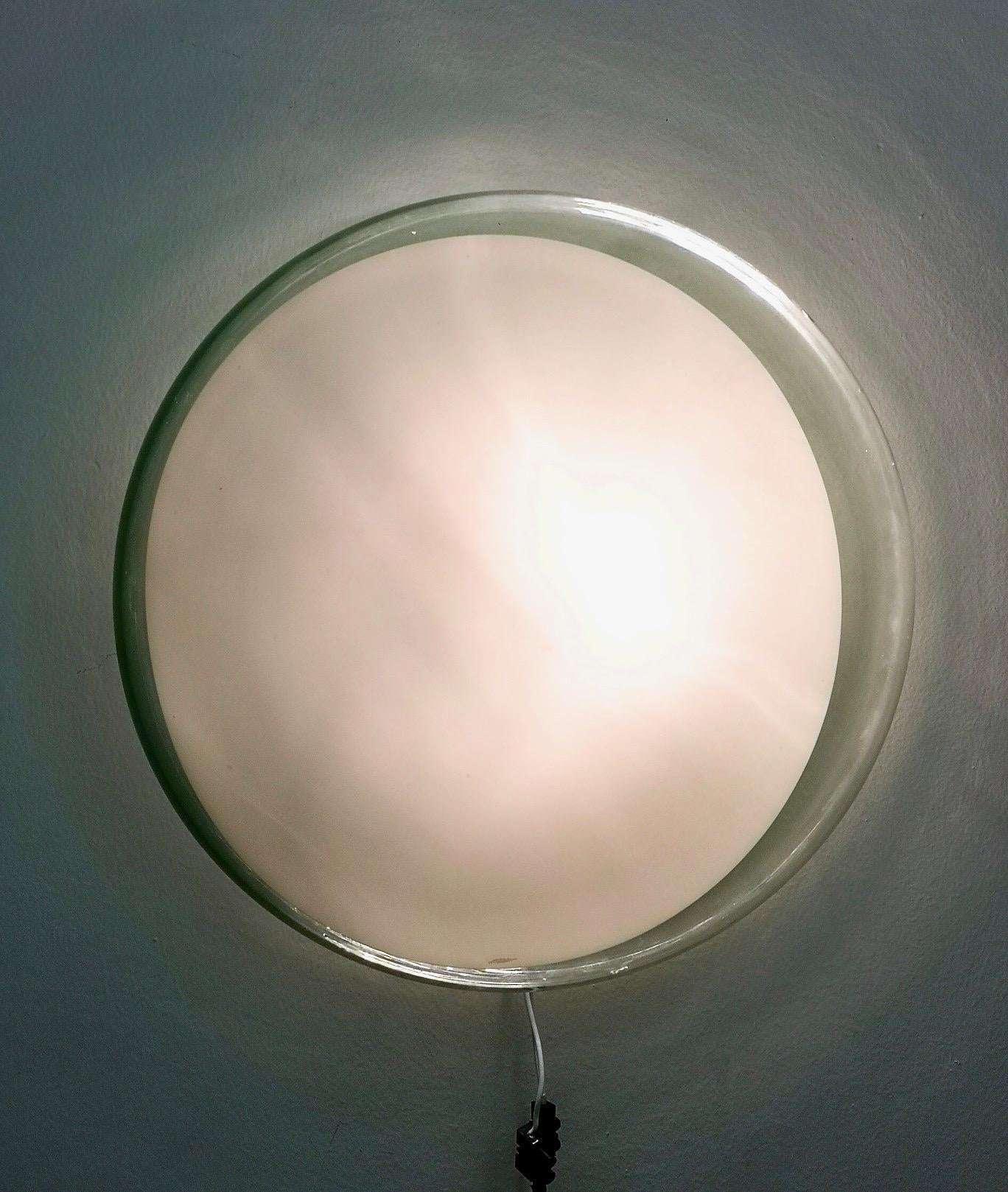 Leucos first designed this in 1962.
Gill is a wall or ceiling mount featuring a round, blown-glass diffuser in clear Murano glass with a circular white detail across the front.
The glass diffuser is held in place with three screws that secure it