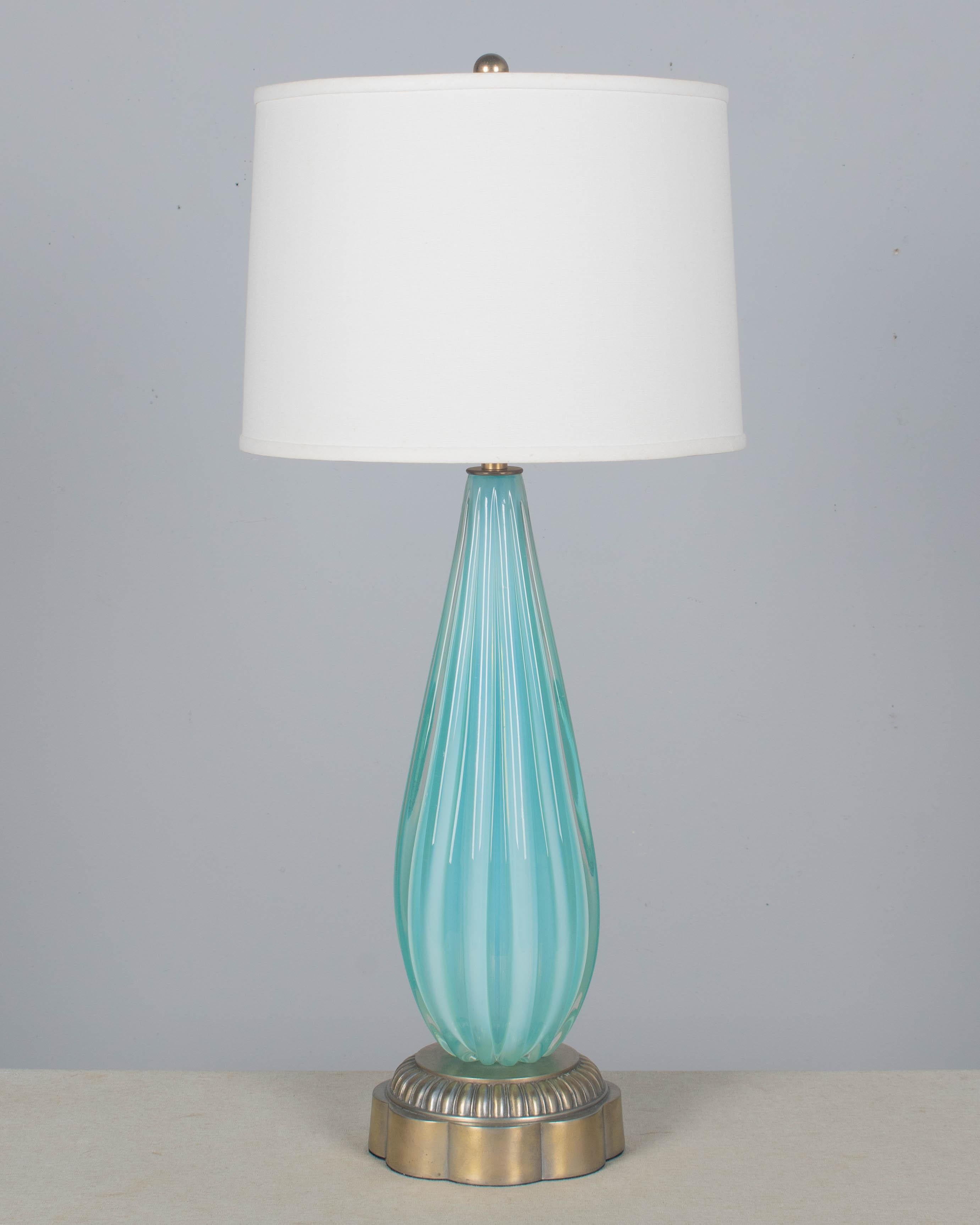 A Mid Century Murano glass lamp by Seguso. Hand-blown aqua cased glass with luminous color and thick ribbed form. Original cast metal base with pale silvery brass finish. Rewired with new socket and cord. Circa 1950s. 
Shade is NOT included but for