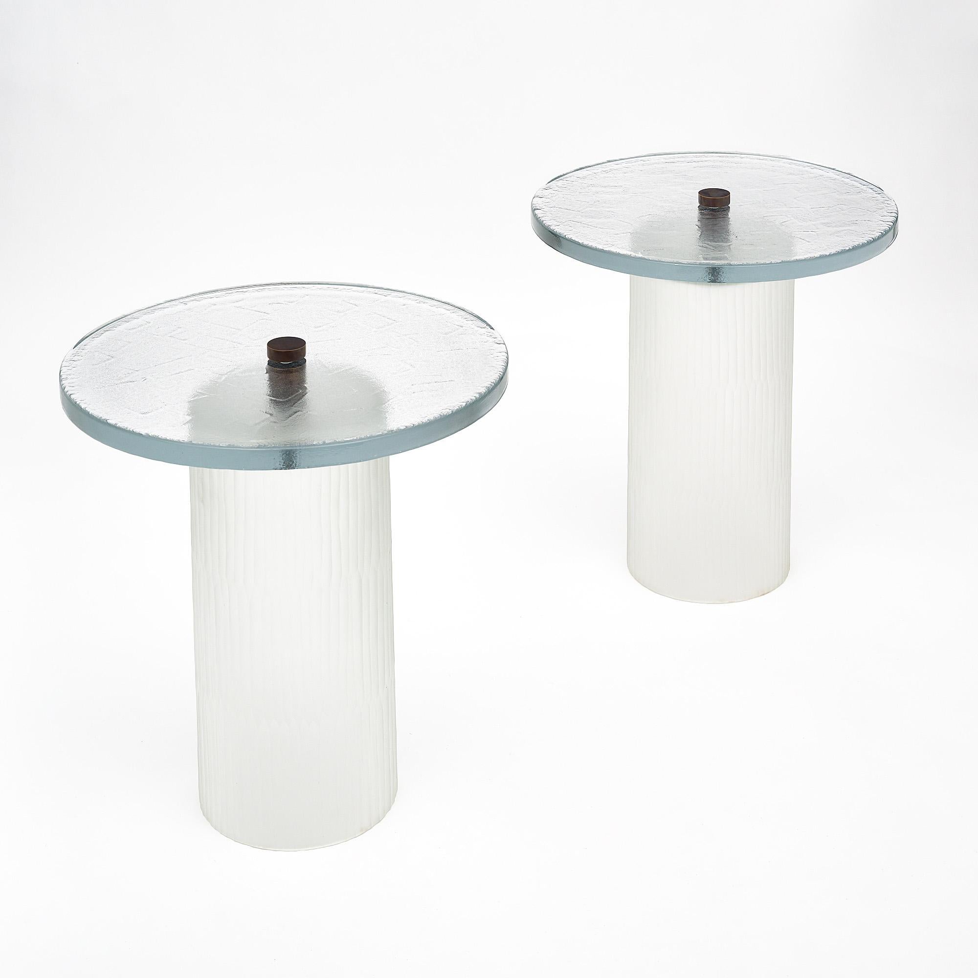 Paire de tables en verre de Murano, en verre épais transparent texturé et moulé. La partie supérieure est reliée à la base par un épi de faîtage en laiton massif. Le diamètre de la base est de 10