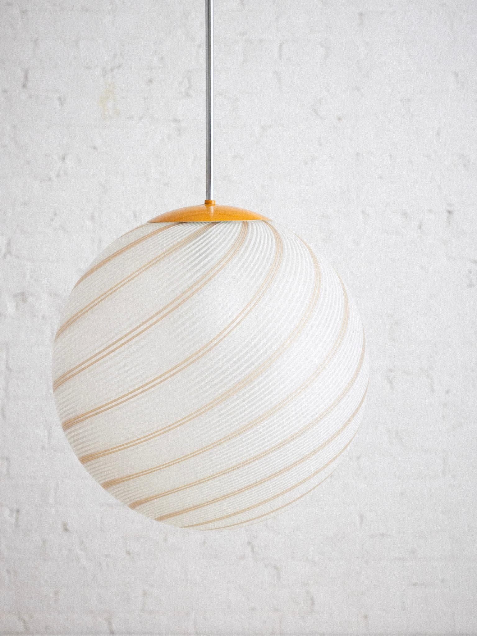 An Italian Murano glass globe pendant light. White and tan spiral pattern with frosted finish. Original chrome and orange coated hardware. Original wiring as found. Sourced in Northern Italy.

Globe measures 16” in diameter. 