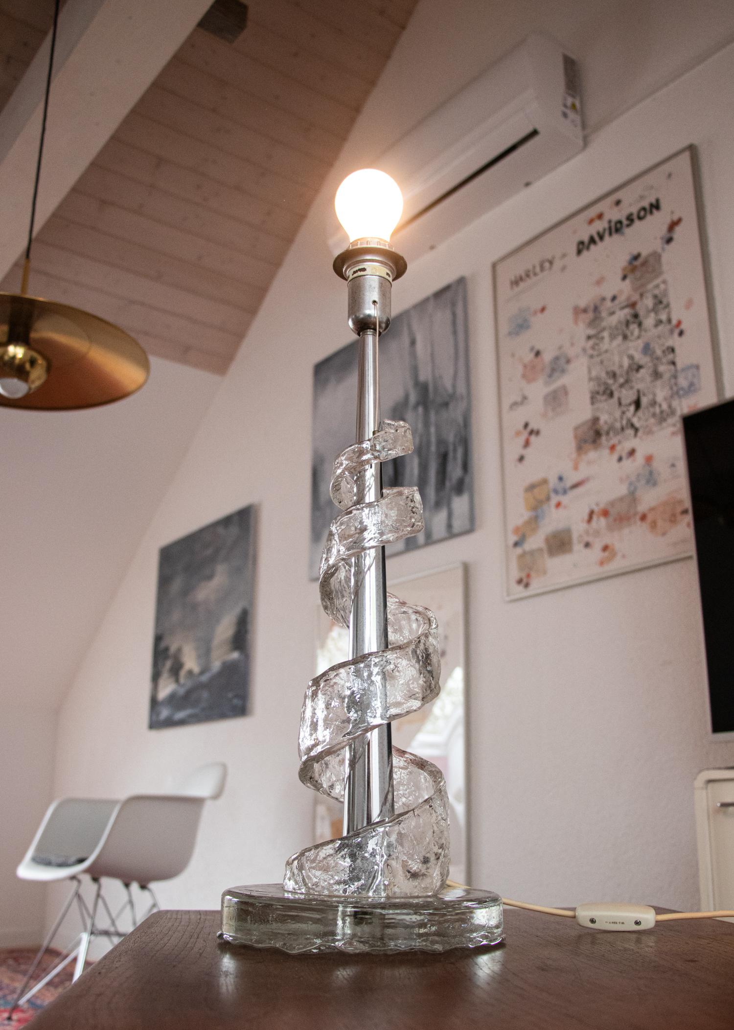 Erstaunliche große Tischlampe aus einer Spirale aus Muranoglas, die sich um einen Chromstab windet.

Schmuckstück aus der Zeit. Auch im unbeleuchteten Zustand ein echter Blickfang. 

Diese Leuchtskulptur ist ein Entwurf von Angelo Brotto für