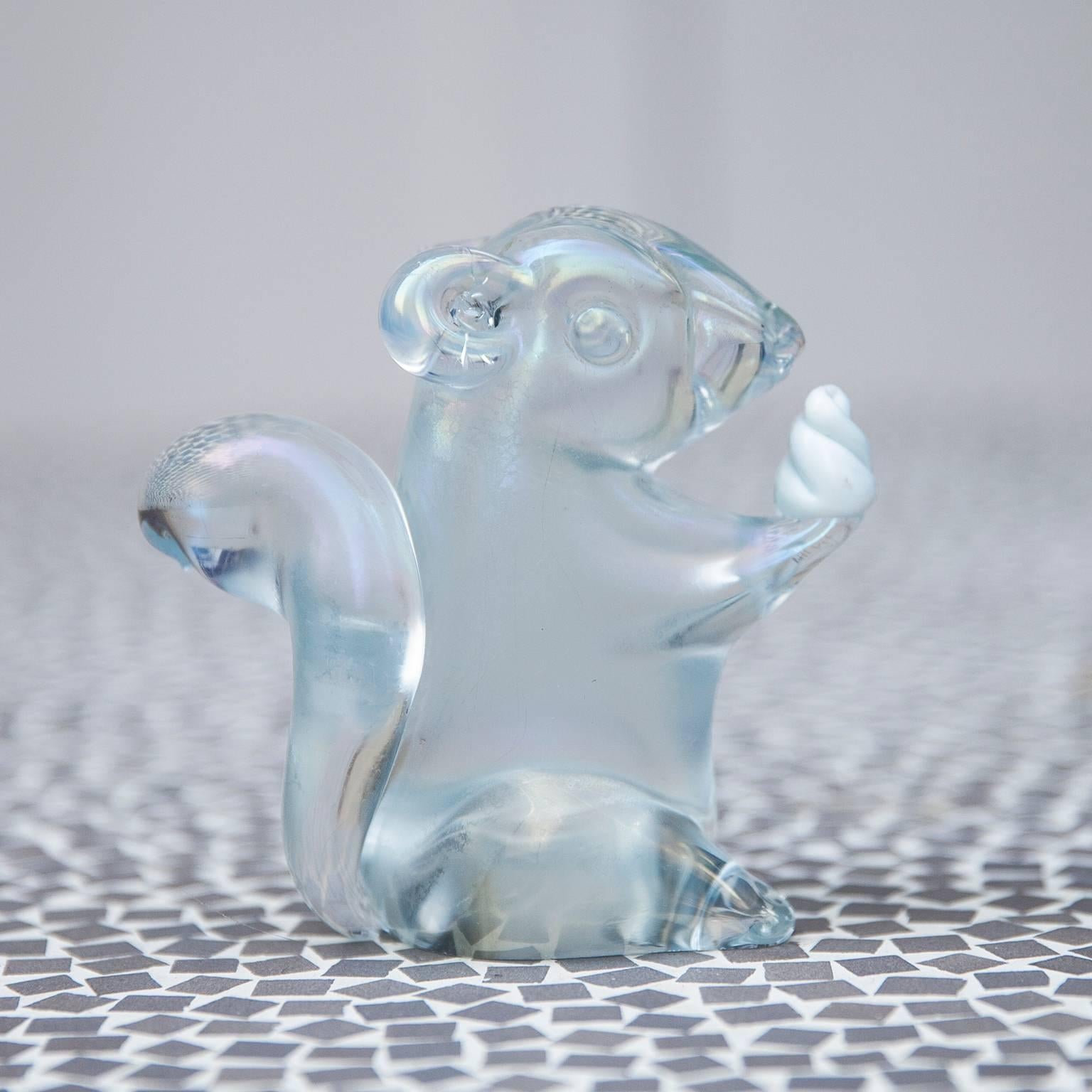 Very cute Murano glass squirrel object made by Seguso in Italy in the 1970s.

Clear glass, iridescent strong and a small white glass nut in the hand.