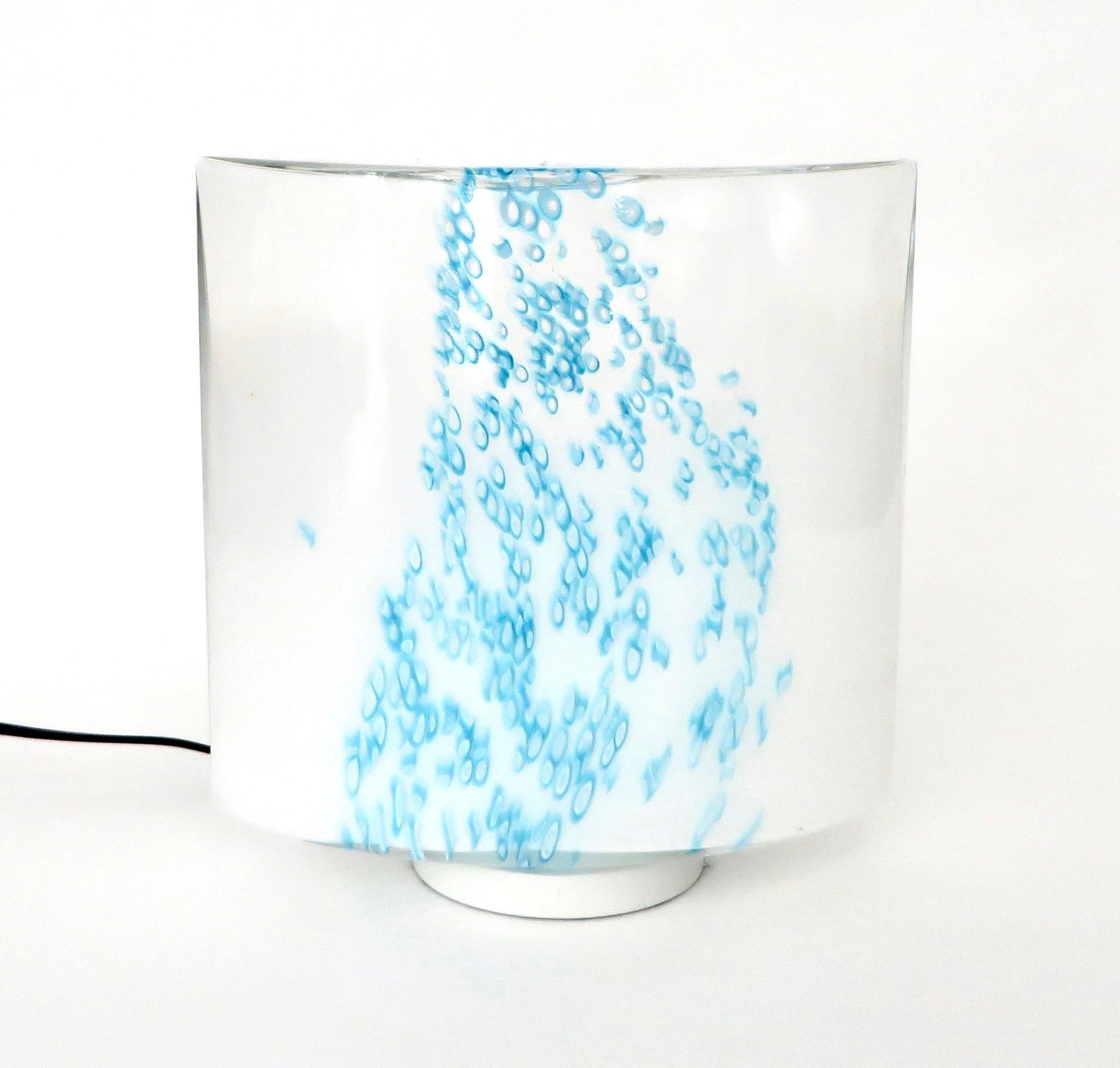 Lampe de table en verre opaque de Murano Leucos avec des coulures de couleur bleu turquoise évoquant la mer ou la pluie.
Il émet une douce lueur bleue lorsqu'il est allumé. 
Une ampoule dans la base.