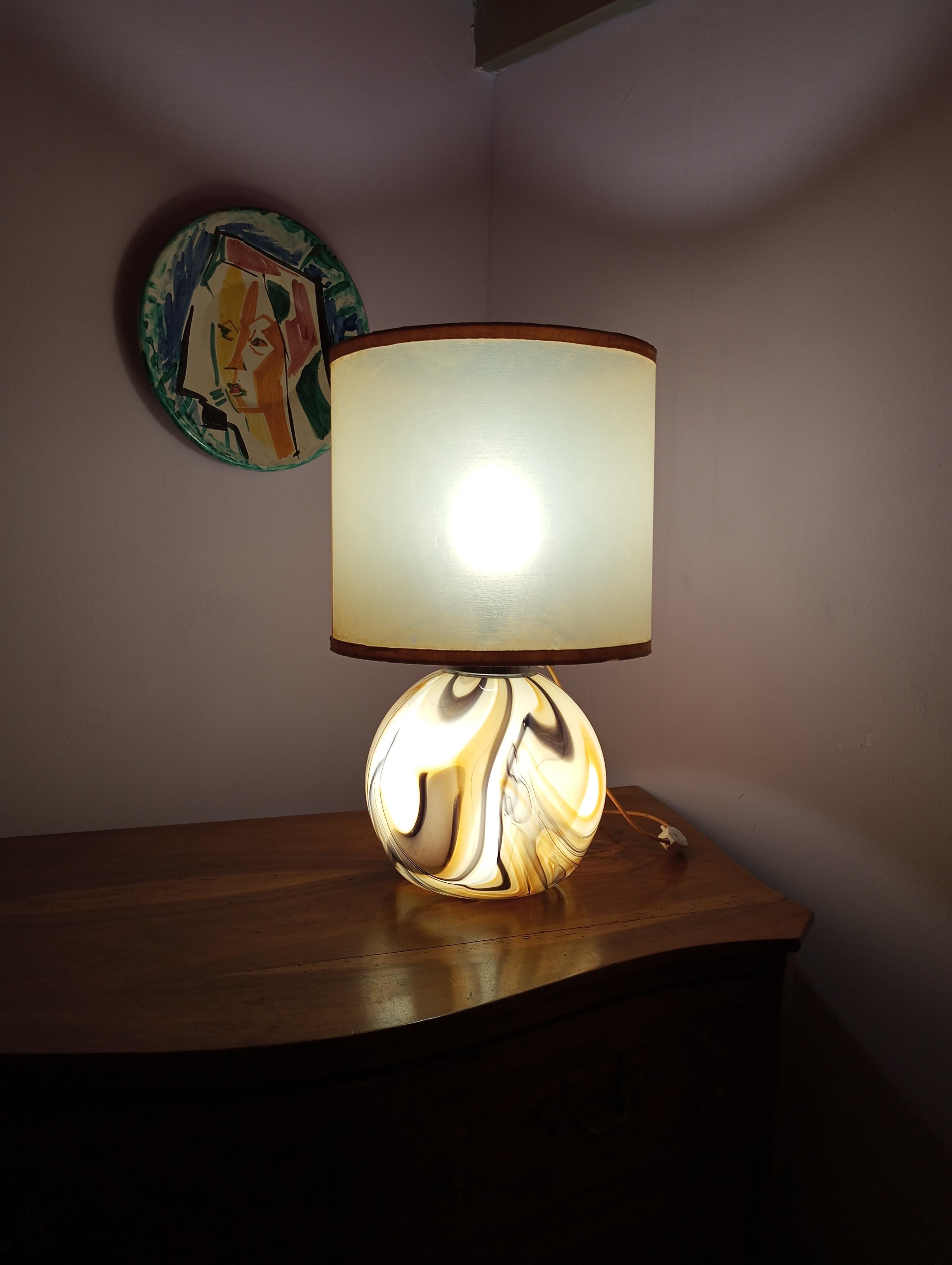  Italian table lamp with a spherical Murano glass base from the '70s. The glass is crafted with brown marble-like shades. The switch has three different positions, allowing you to independently turn on the two bulbs or both together. Lampshade