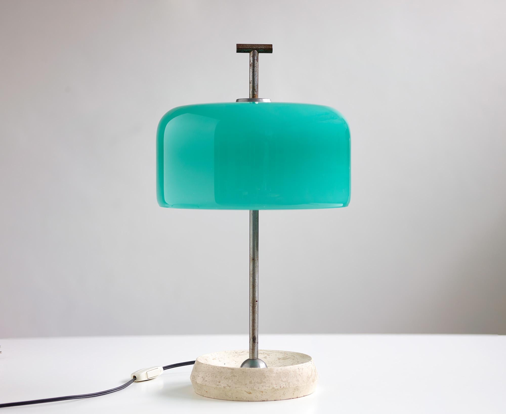 Stunning table lamp attributed to Italian glass manufacturer Vistosi.

This very well crafted table lamp boast a beautiful emerald green Murano glass shade with 3 E14 light sources and a round travertine base with beveled edges.

When illuminated