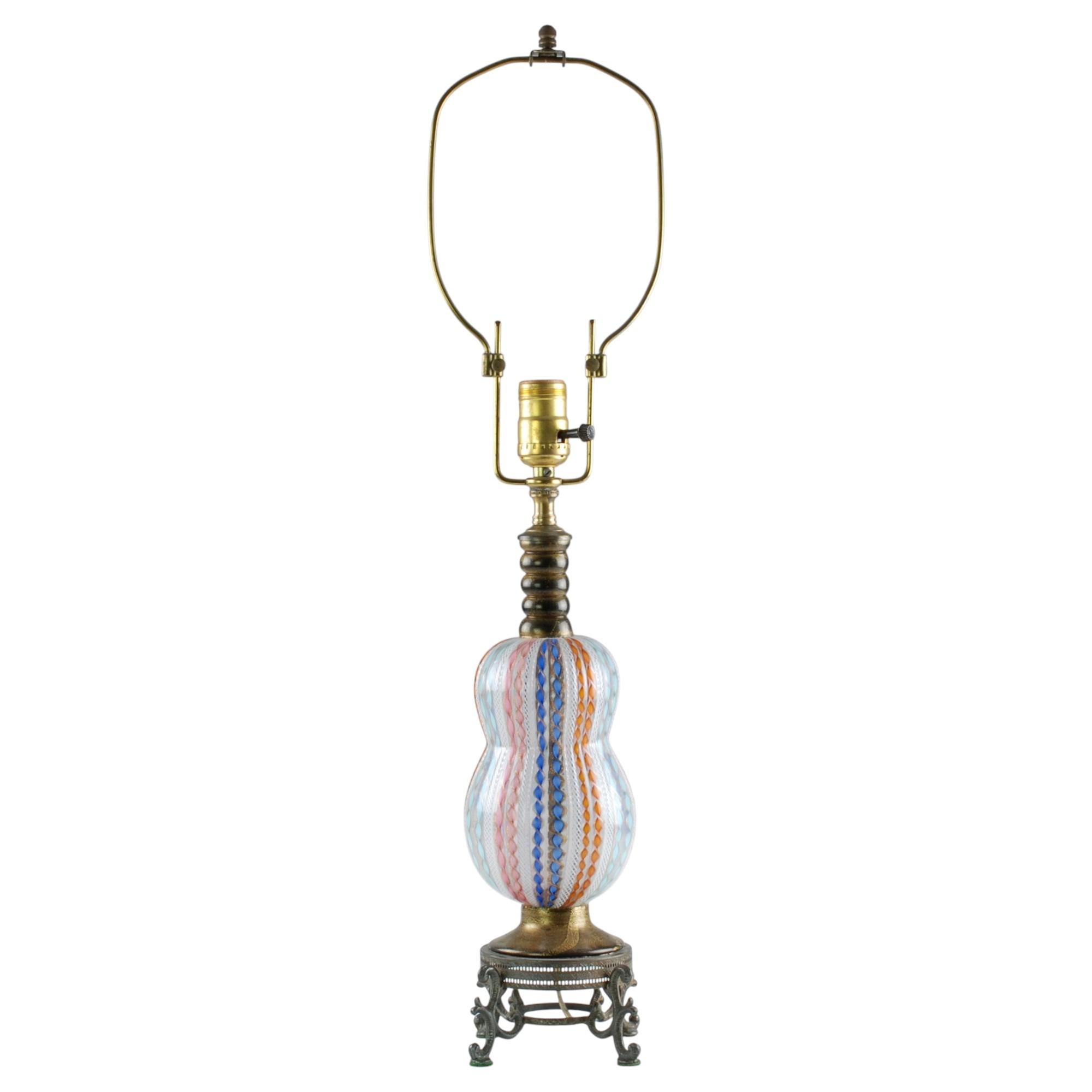 Esta lámpara de mesa de cristal italiano de Murano soplado a mano tiene una forma orgánica de doble calabaza o calabacín que descansa sobre una base de pedestal de cristal negro decorada con lavados dorados. El cuerpo de la pieza presenta decoración