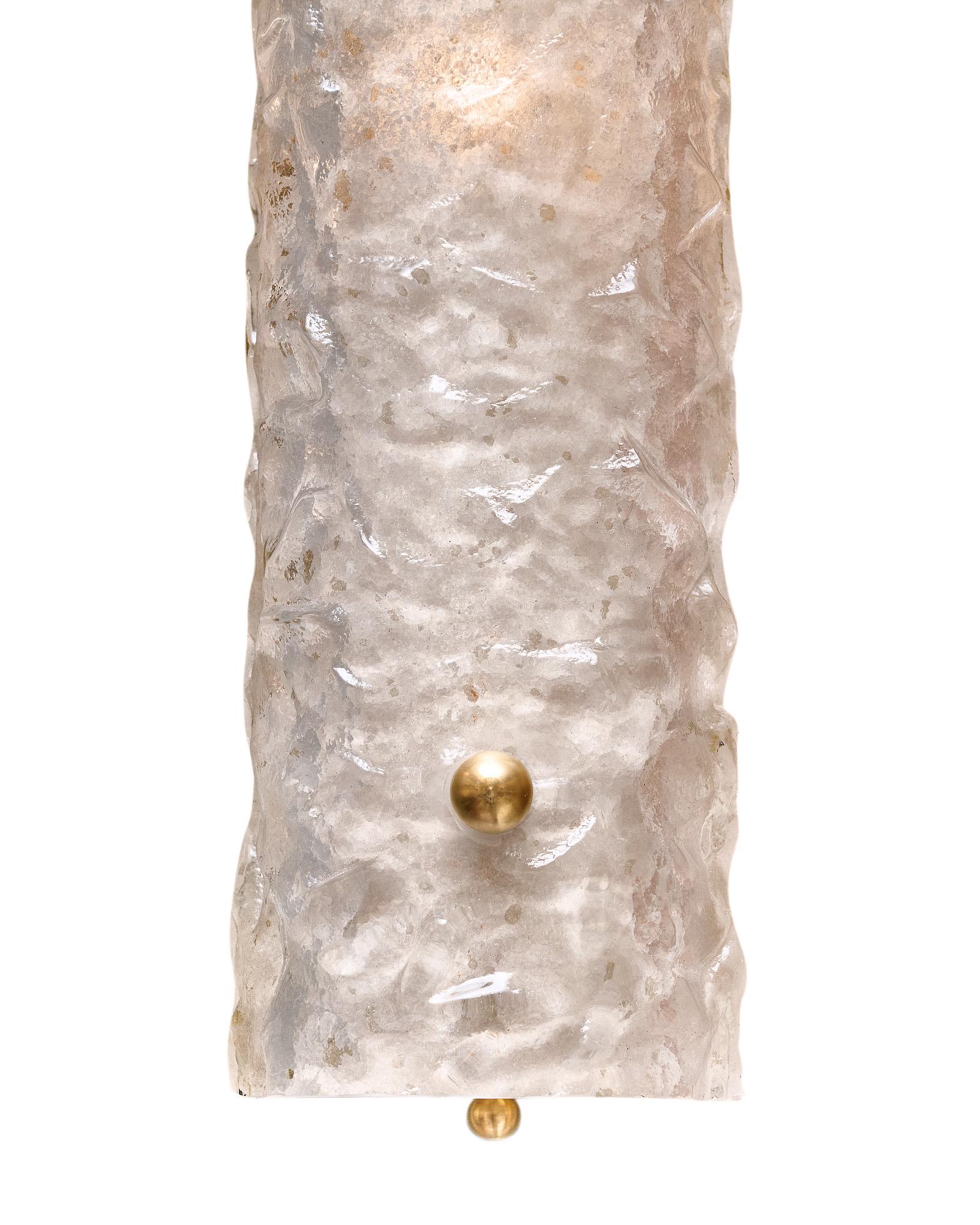 Pair of sconces made of hand-blown glass with a textured stampato finish. The glass is in a pearlescent color and is held in place by brass finials. They have been newly wired to fit US standards.