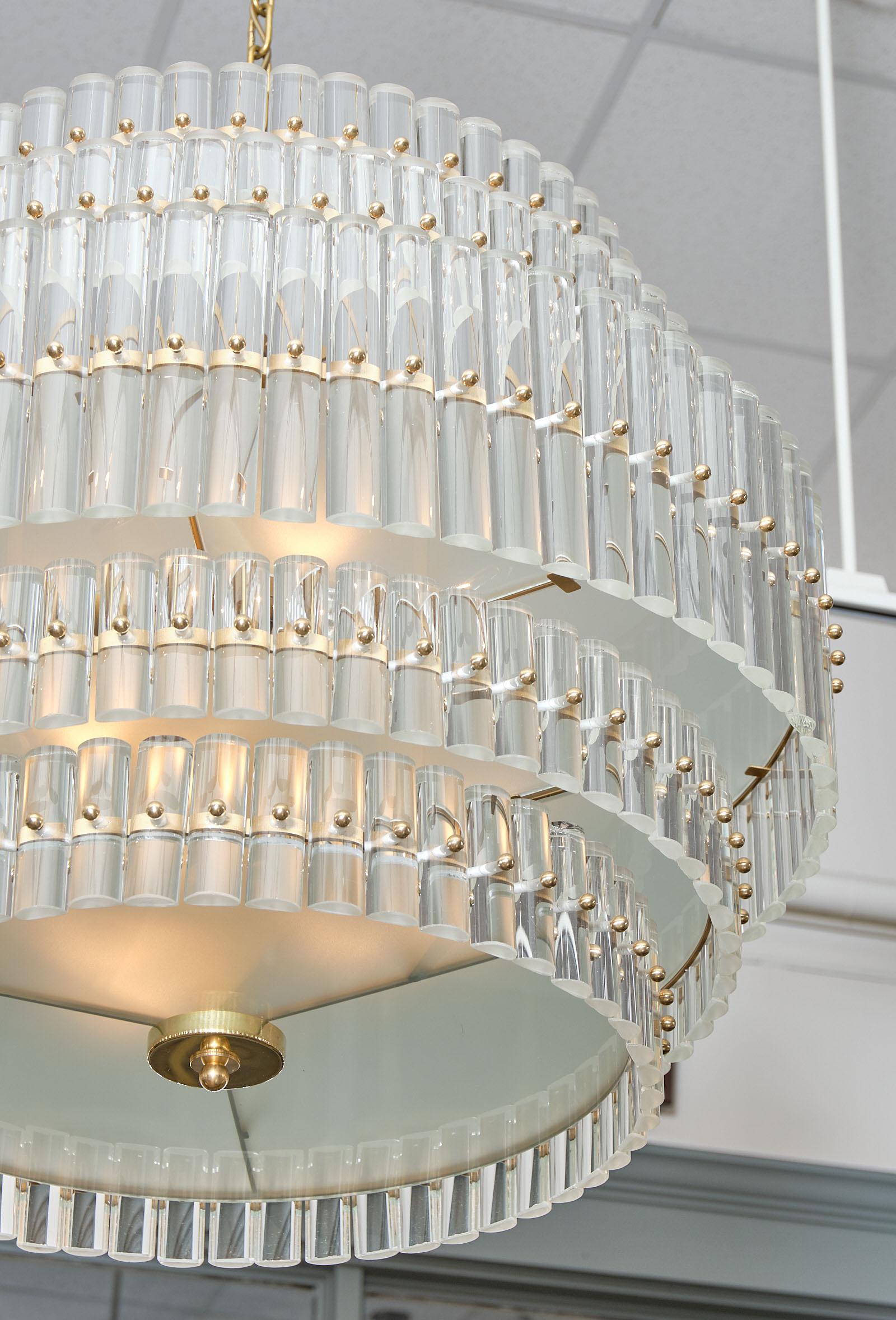 Murano glass tiered rod chandelier from the island of Murano in Italy. This piece features a gilt brass structure supporting five rows of clear glass rods hand blown by artisans in Murano. We love the glamorous way the light filters through the