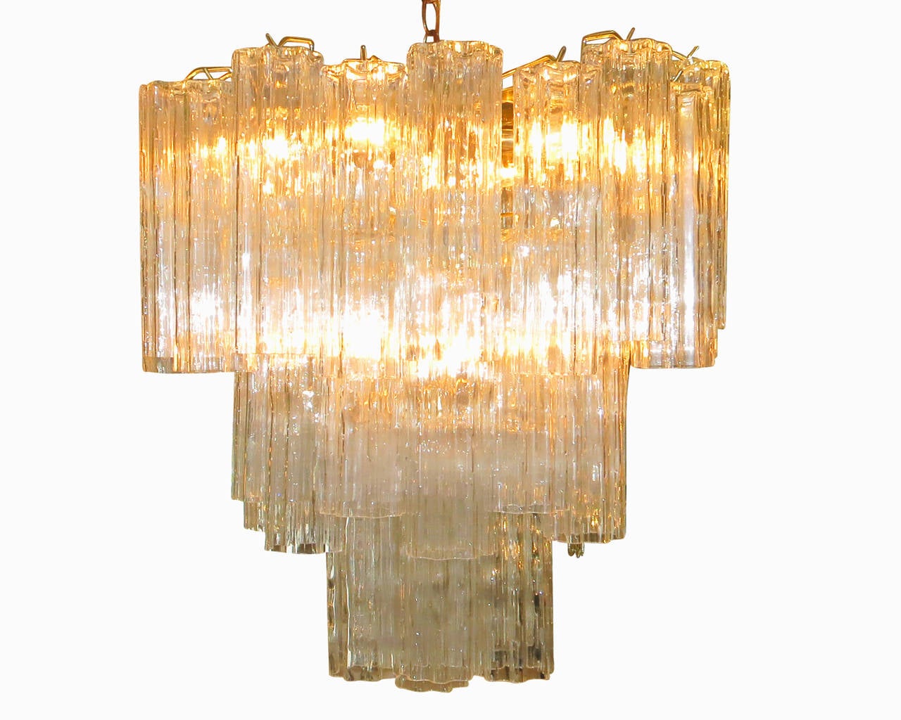 Made in Italy, this gorgeous Venini round chandelier features a brass frame and three tiers of textured glass pendants, known as tronchi. The light glistens through the glass pendants, which are uniform in shape and size. 

Note that the