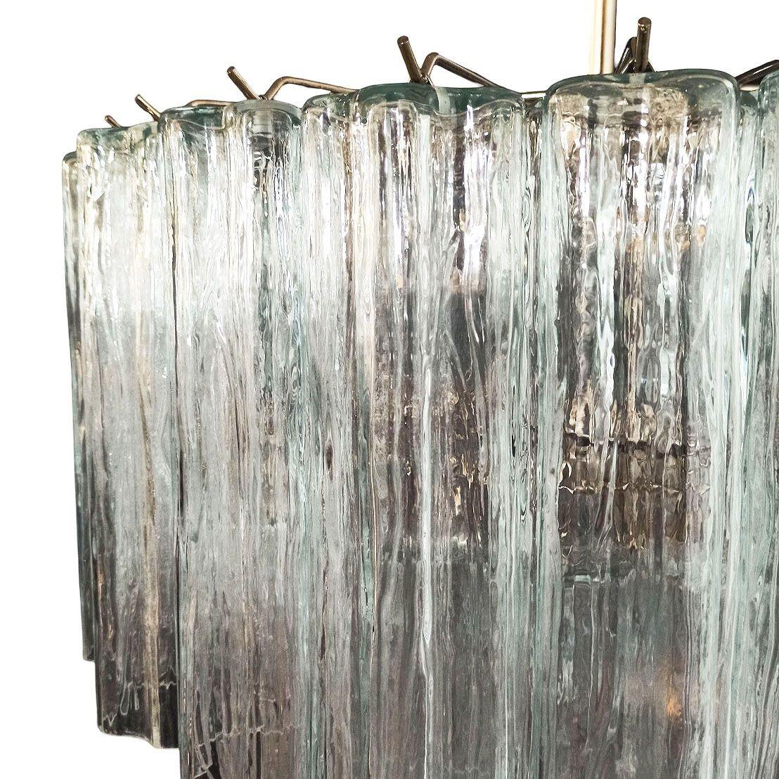 Fabricada en Italia, esta preciosa lámpara de araña redonda tiene una estructura de latón y tres hileras de colgantes de cristal texturizado, conocidos como tronchi de Venini. La luz brilla a través de los colgantes de cristal, que son uniformes en