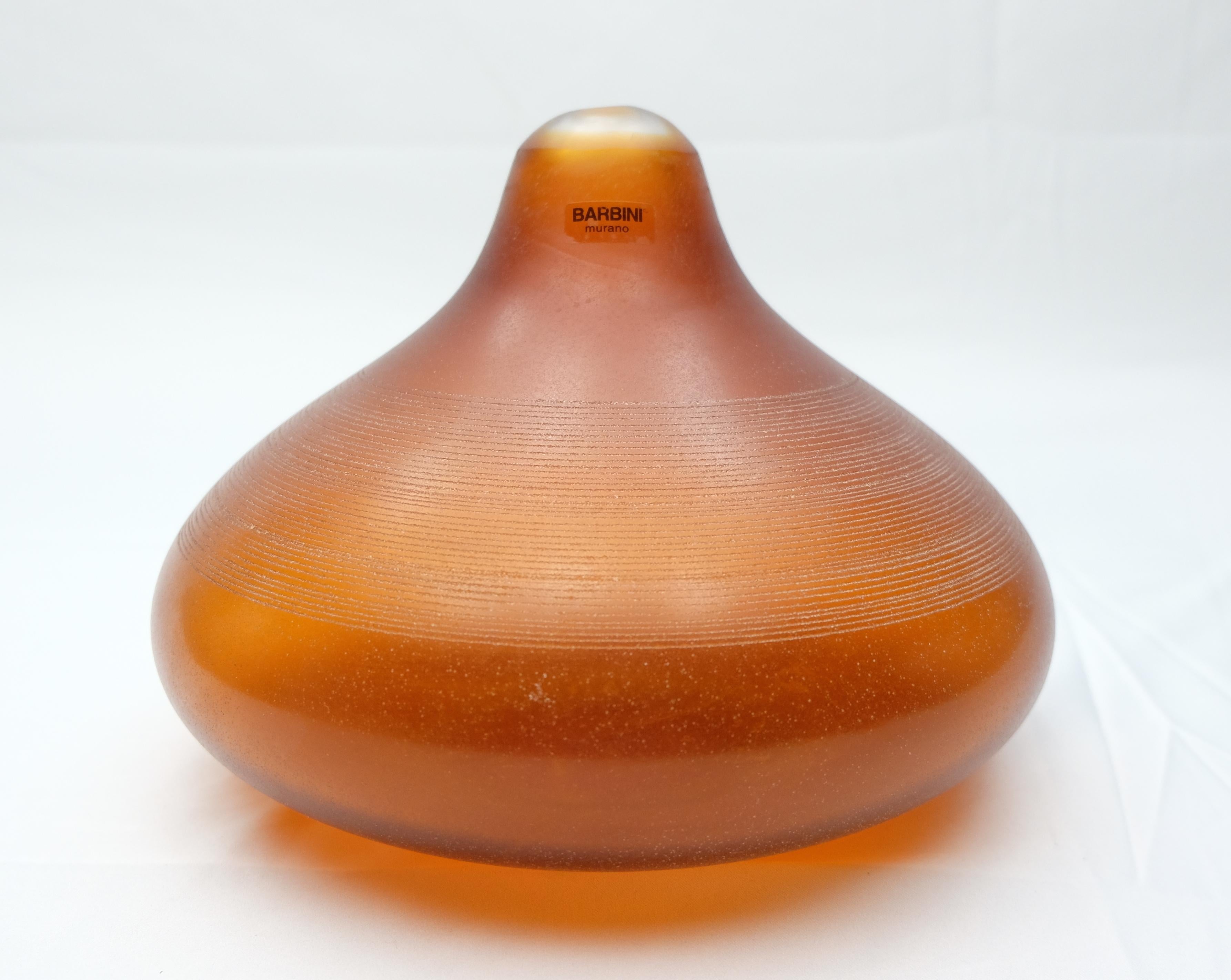Offered for sale is an amber round blown Murano glass single stem vase from Barbini. The sculptural form is organic and is complemented by the natural coloring. The vase is lightly textured and scored with a polished top. The piece is signed on the