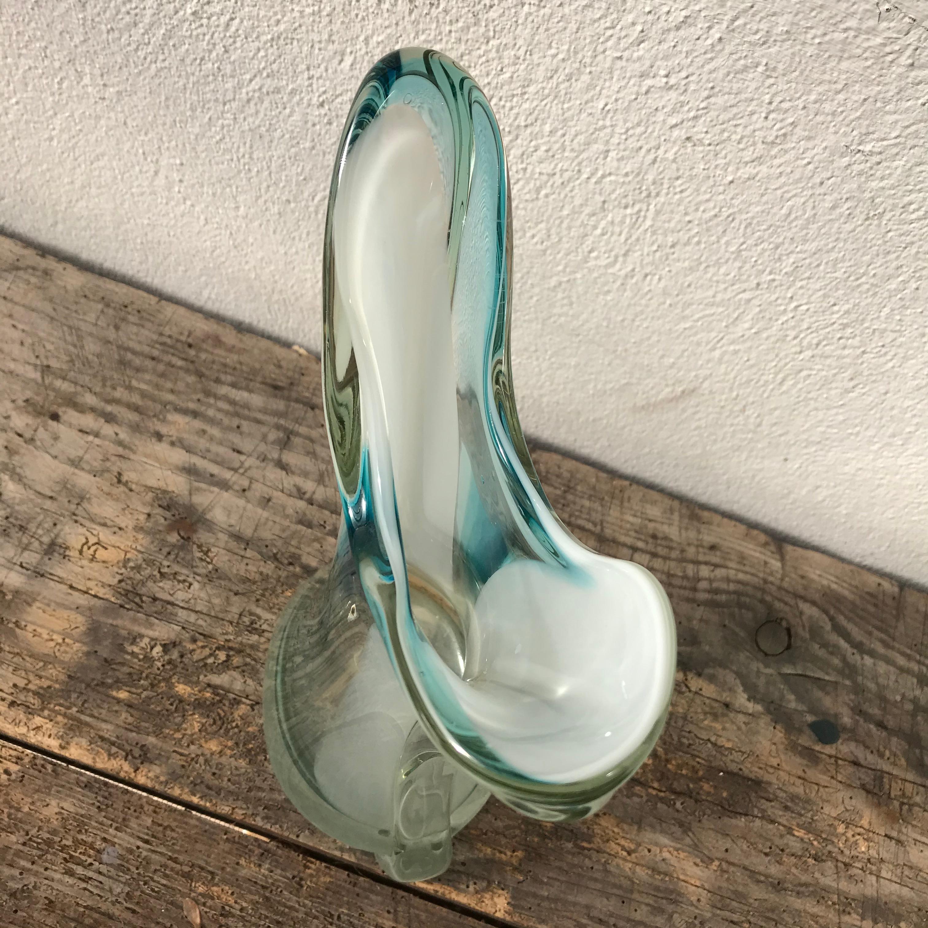 Elegia il tuo arredamento con questo vaso in vetro di Murano dalle splendide tonalità ciano-trasparenti, un capolavoro di artigianato veneziano e di eleganza senza tempo.