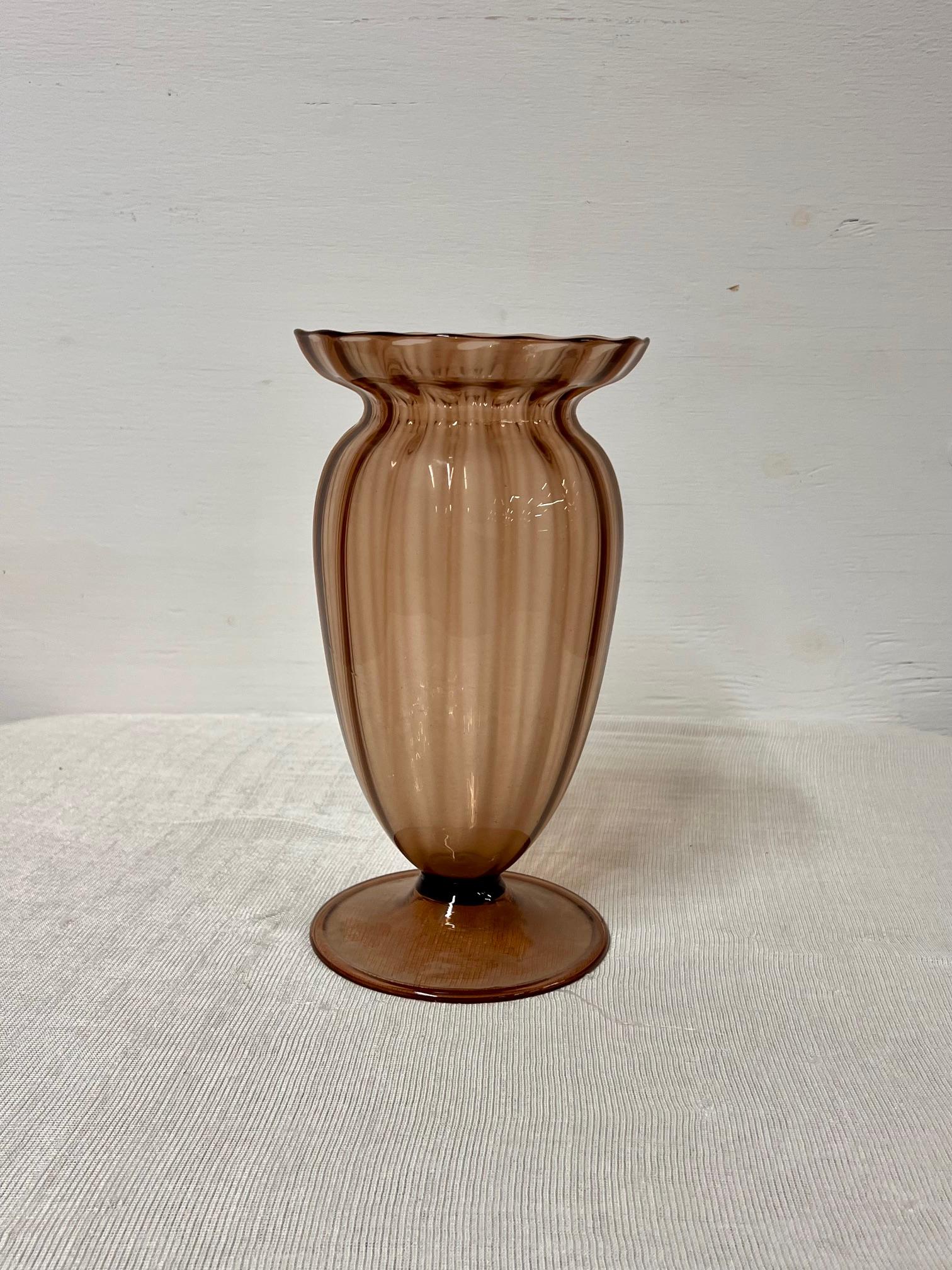 Vaso in vetro di Murano vintage
Il vaso è realizzato in vetro soffiato a mano color ametista con un design a coste.
Lo stile è attribuito alla vetreria Fratelli Toso, un'azienda di Murano fondata nel 1854.
Presenta un bordo arricciato e una base a