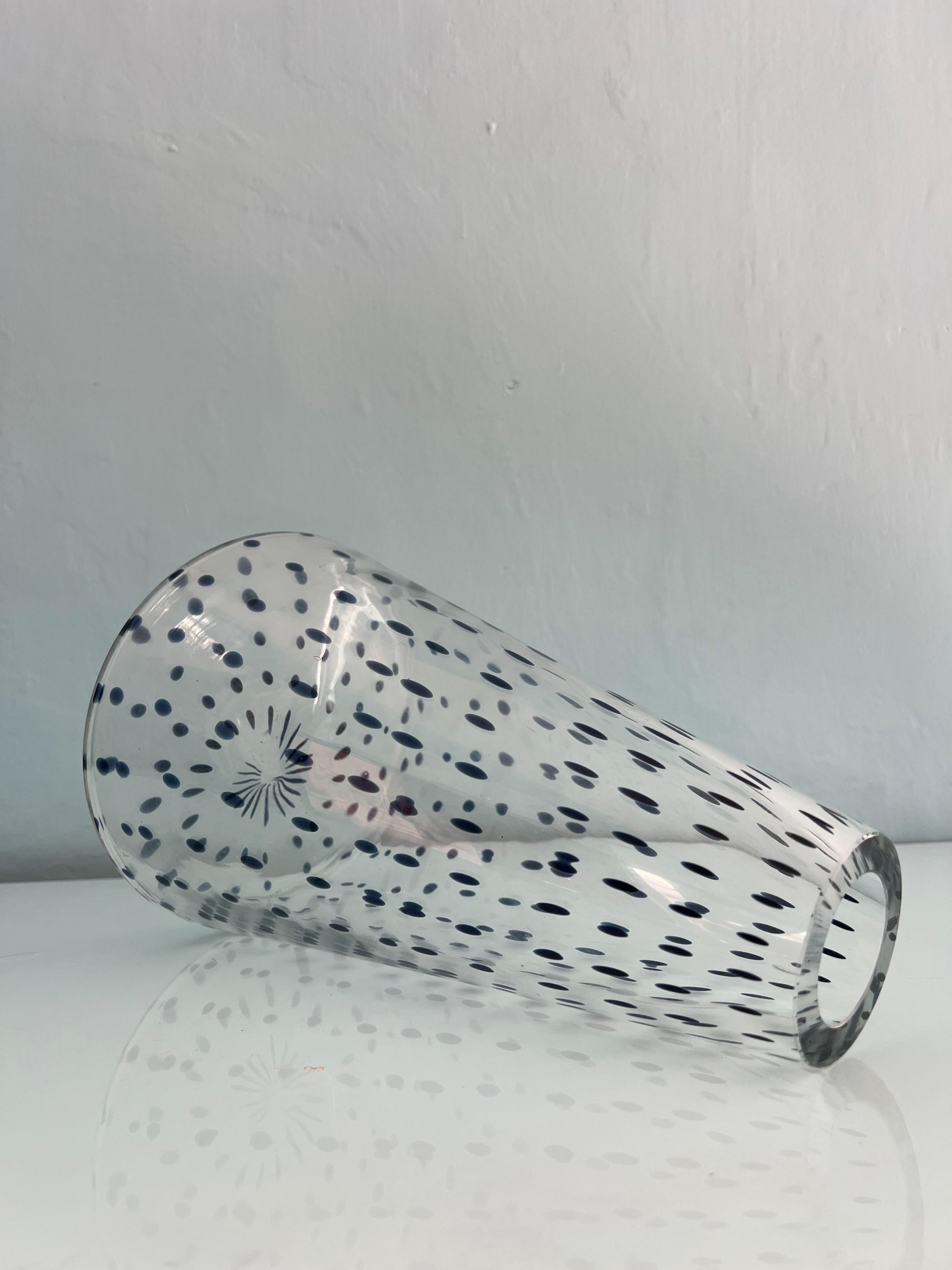 Questo vaso in vetro di Murano è il modello Gisa di Rosanna Toso per Fratelli Toso degli anni Settanta.
Il vaso ha un corpo conico trasparente con un motivo grafico di punti blu intenso che sembrano fluttuare all'interno del vetro e salire verso