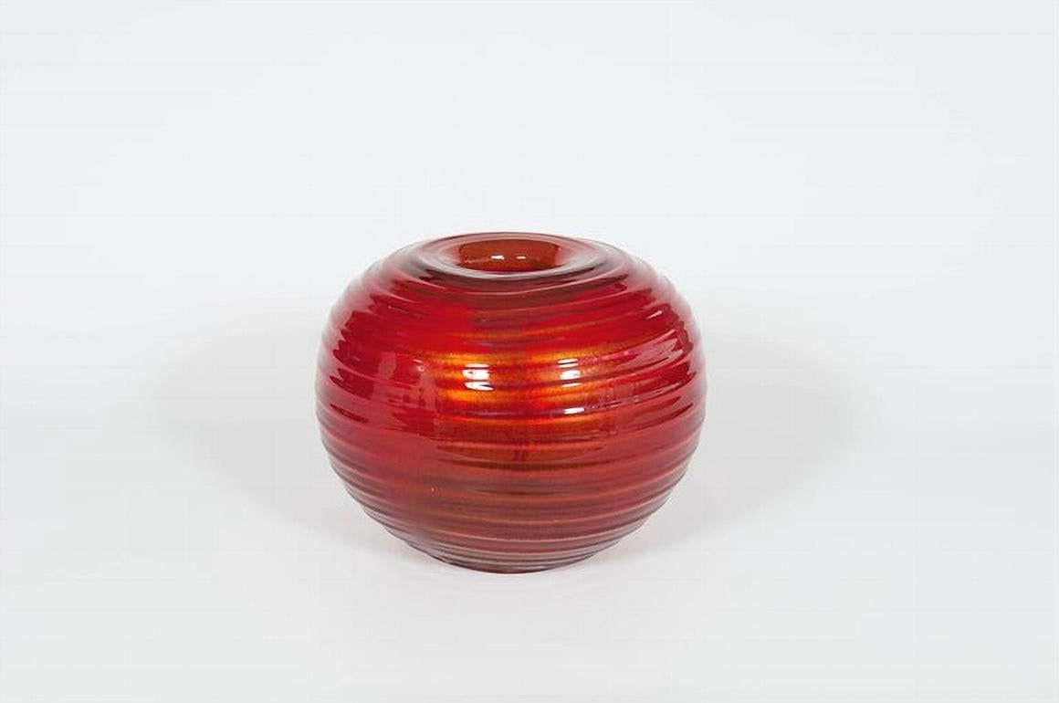 Murano glass vase in vibrant red adorned by a central gold pendant Italy 1980s.

This exceptional Murano glass vase, crafted in the 1980s, is a striking piece of decorative art. Its expansive form, reminiscent of a bowl, is accentuated by a rich,
