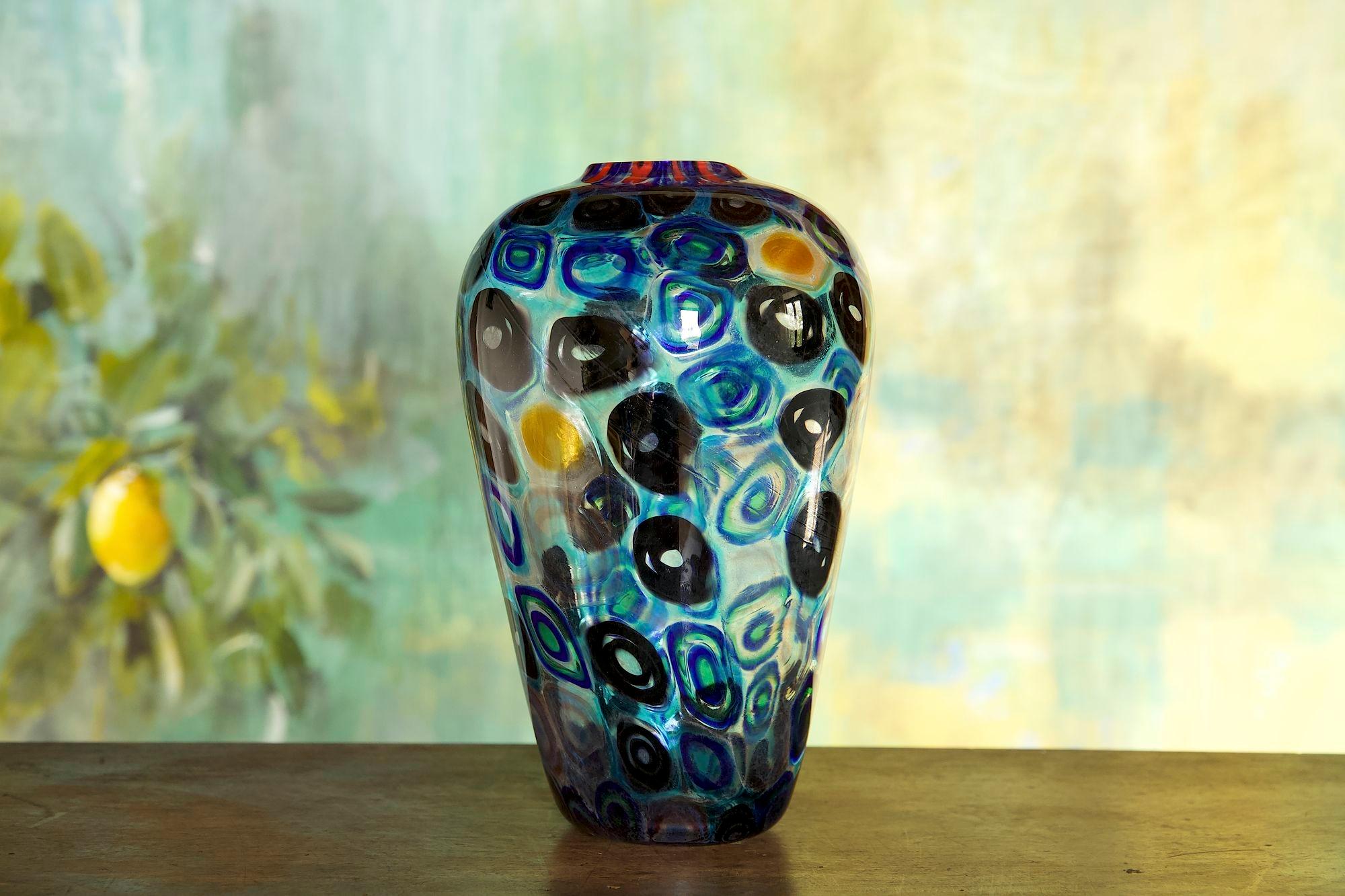 Enchanting collectible Murano vase with hot-applied murrine of various colors predominantly blue and black.
The type of murrine and their arrangement are reminiscent of the creations of the Fratelli Toso.
The murrine mosaic is spotted with isolated