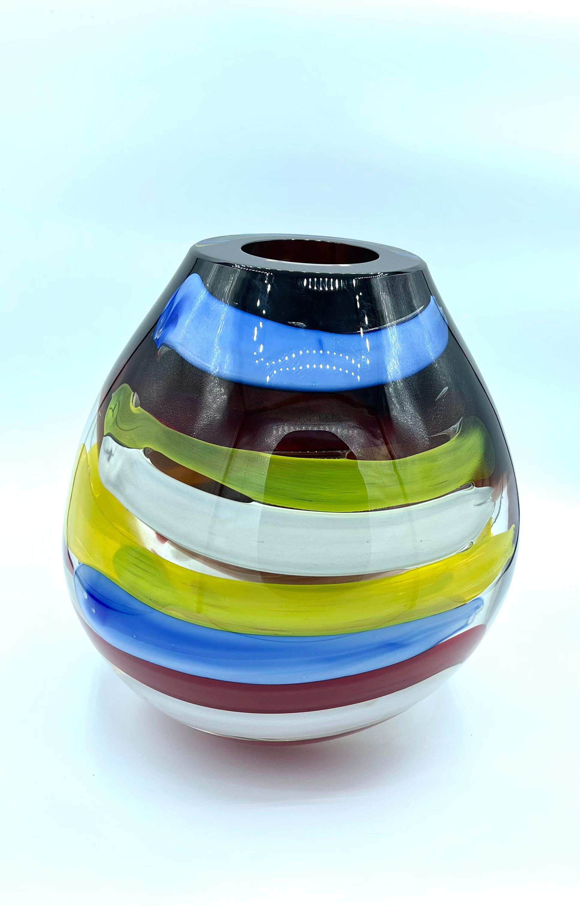 This colorful vase is a unique piece in both its form and colors. To create it, various layers of Murano glass must be overlaid using the incalmo technique, which is a glassworking method that allows the crafting of objects consisting of distinct