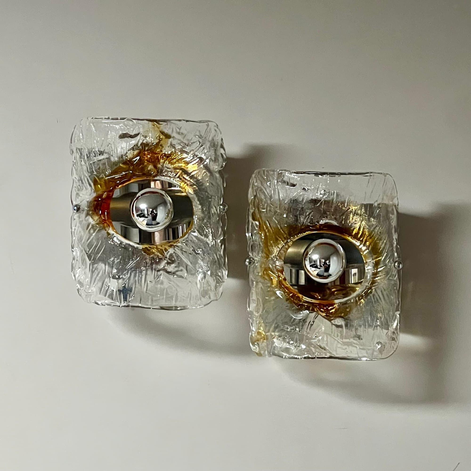 Transport yourself to the glamorous era of the Seventies with this rare pair of Vintage 70s Lamps made of Murano Glass and meticulously crafted in Italy. These exquisite wall lights embody the quintessential style of Carlo Nason designs, coupled