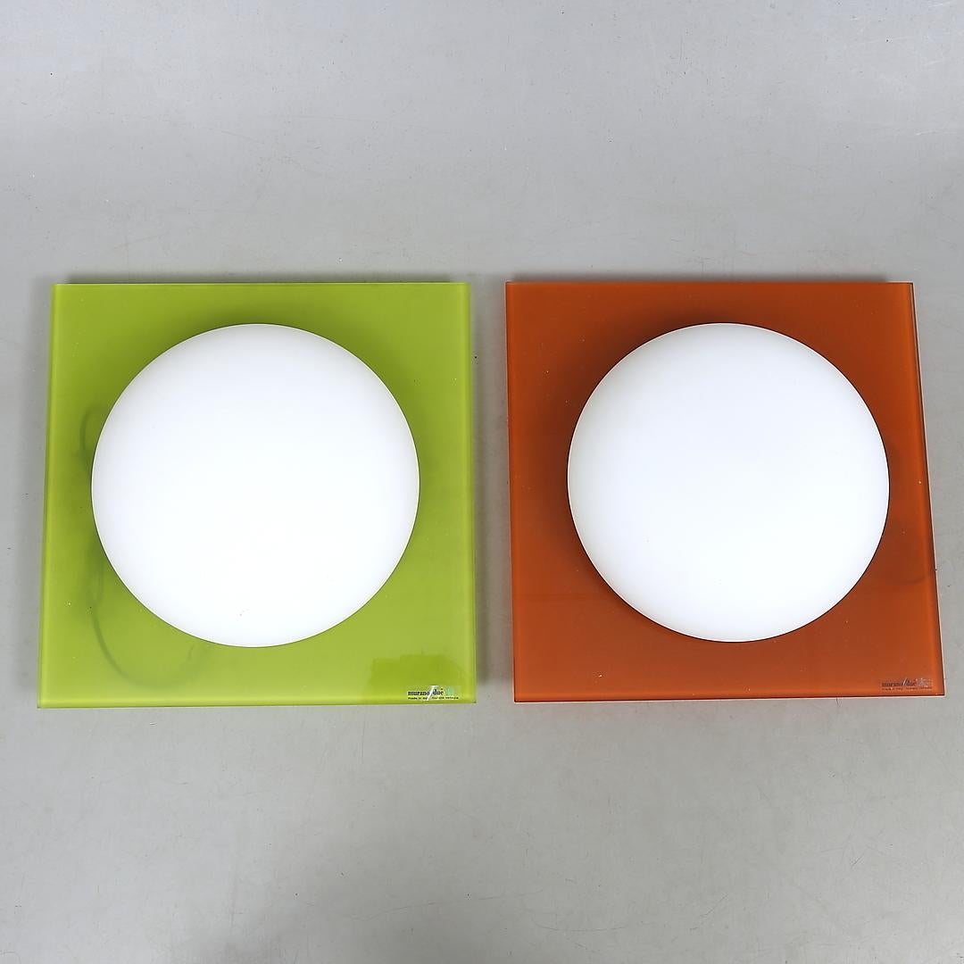 Les lampes Gio, conçues de main de maître par Michele Sbrogiò, utilisent une structure plate simple pour encadrer élégamment une explosion de lumière émise par le diffuseur soufflé à la main en verre opalin blanc satiné. Ces Luminaires présentent