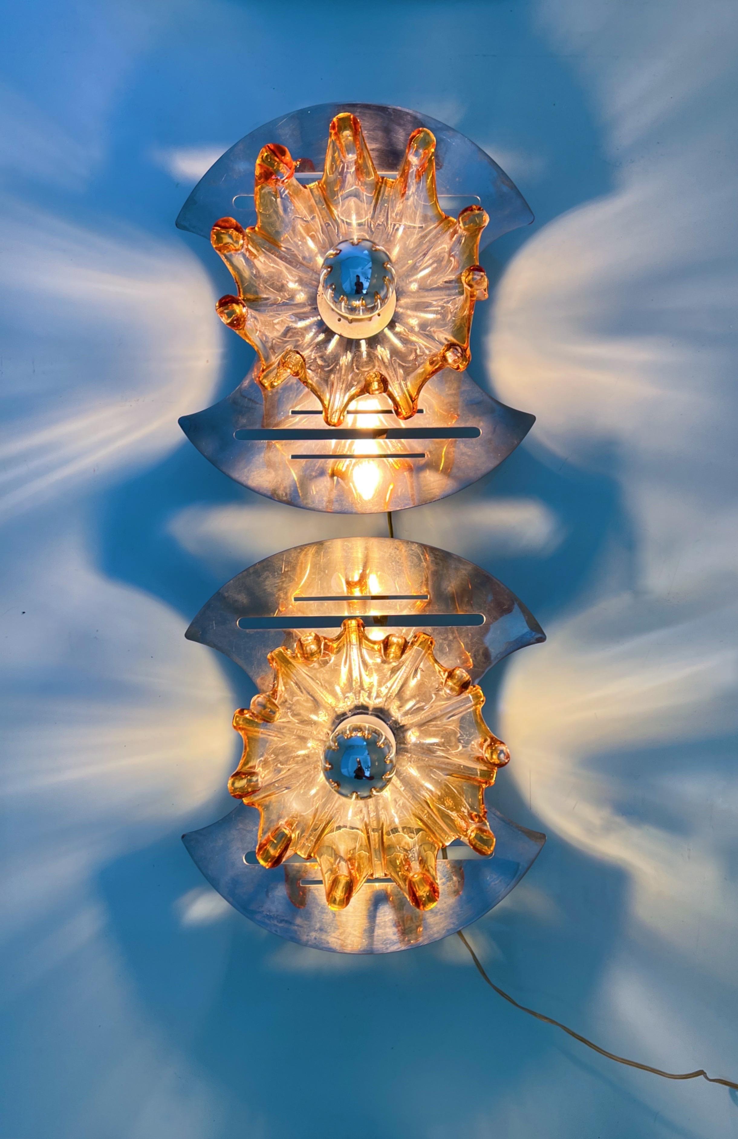 Wall light envisioned by the Italian designer Carlo Nason. This masterpiece features a Murano glass flower delicately placed upon a futuristic metal base. The interplay of light and shadow these fixtures create is nothing short of