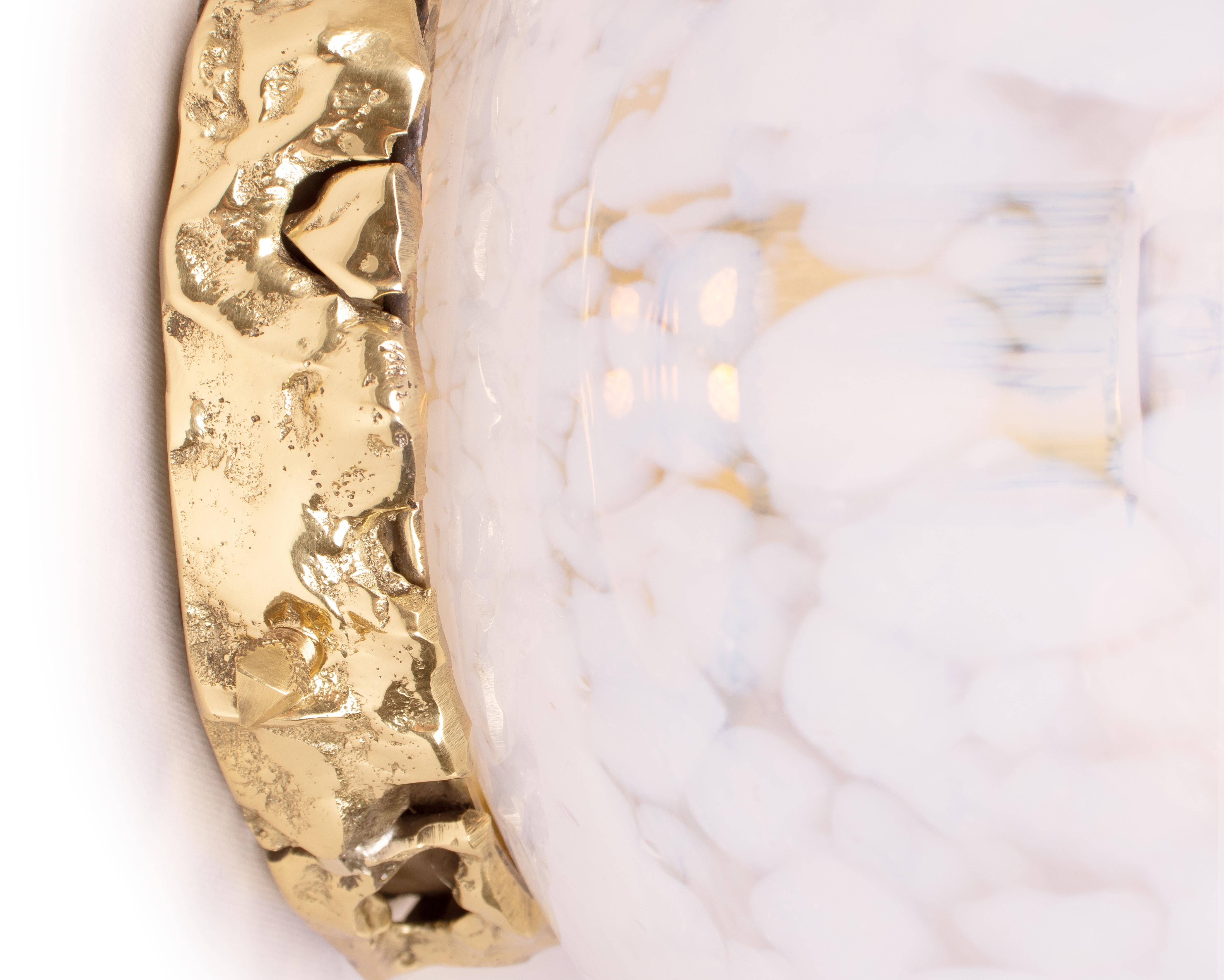 Introducing the Crown Wall Lamp – a radiant fixture designed to elevate your living room, bedroom, or any space you wish to imbue with luxury and elegance. Its base is crafted from cast brass, featuring an irregular, organically textured surface