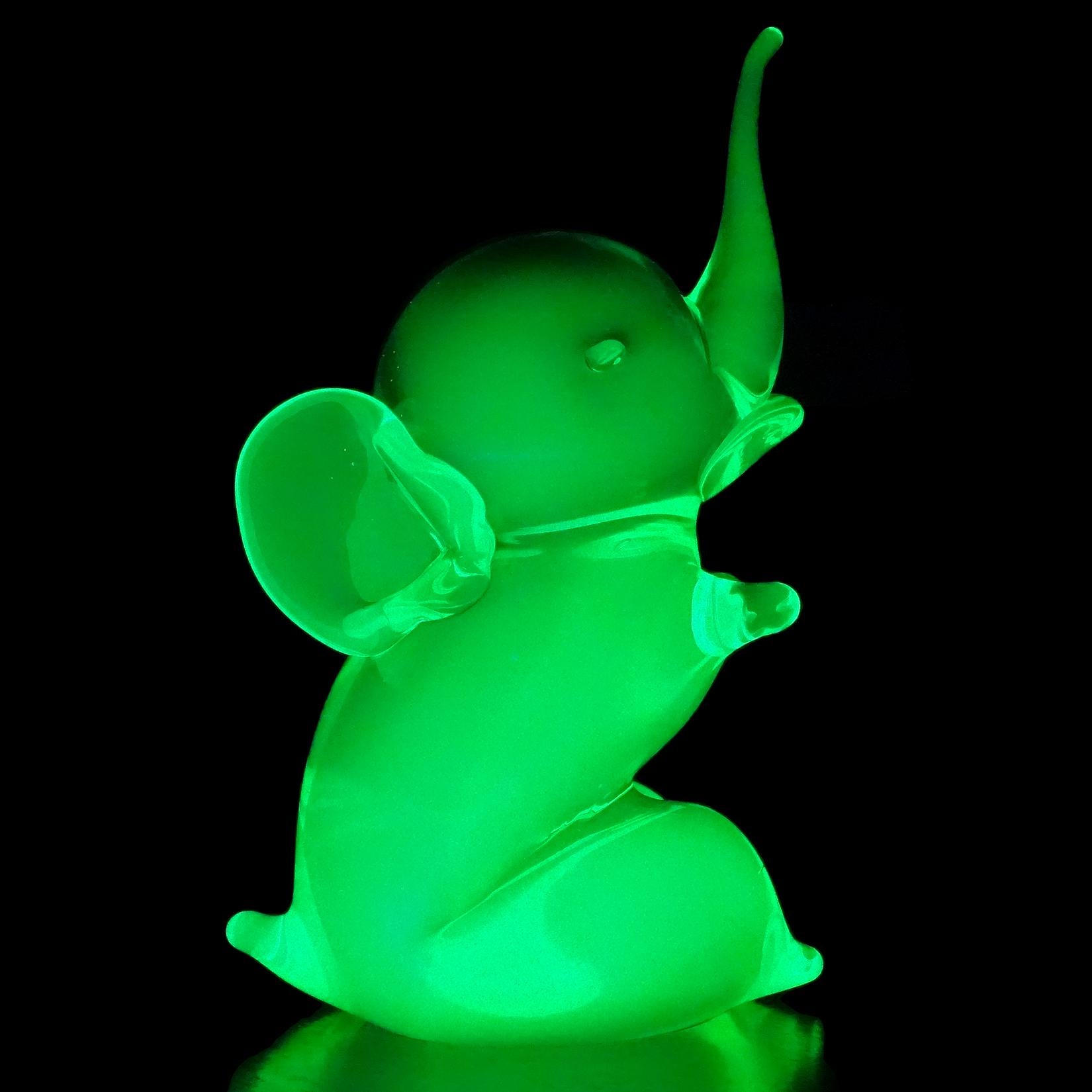 Beautiful cute Murano hand blown green and uranium neon green Italian art glass baby elephant sculpture. Attributed to the Cenedese Company. The figure lights up under a black light, glowing, because of the high uranium glass content. Measures: 5