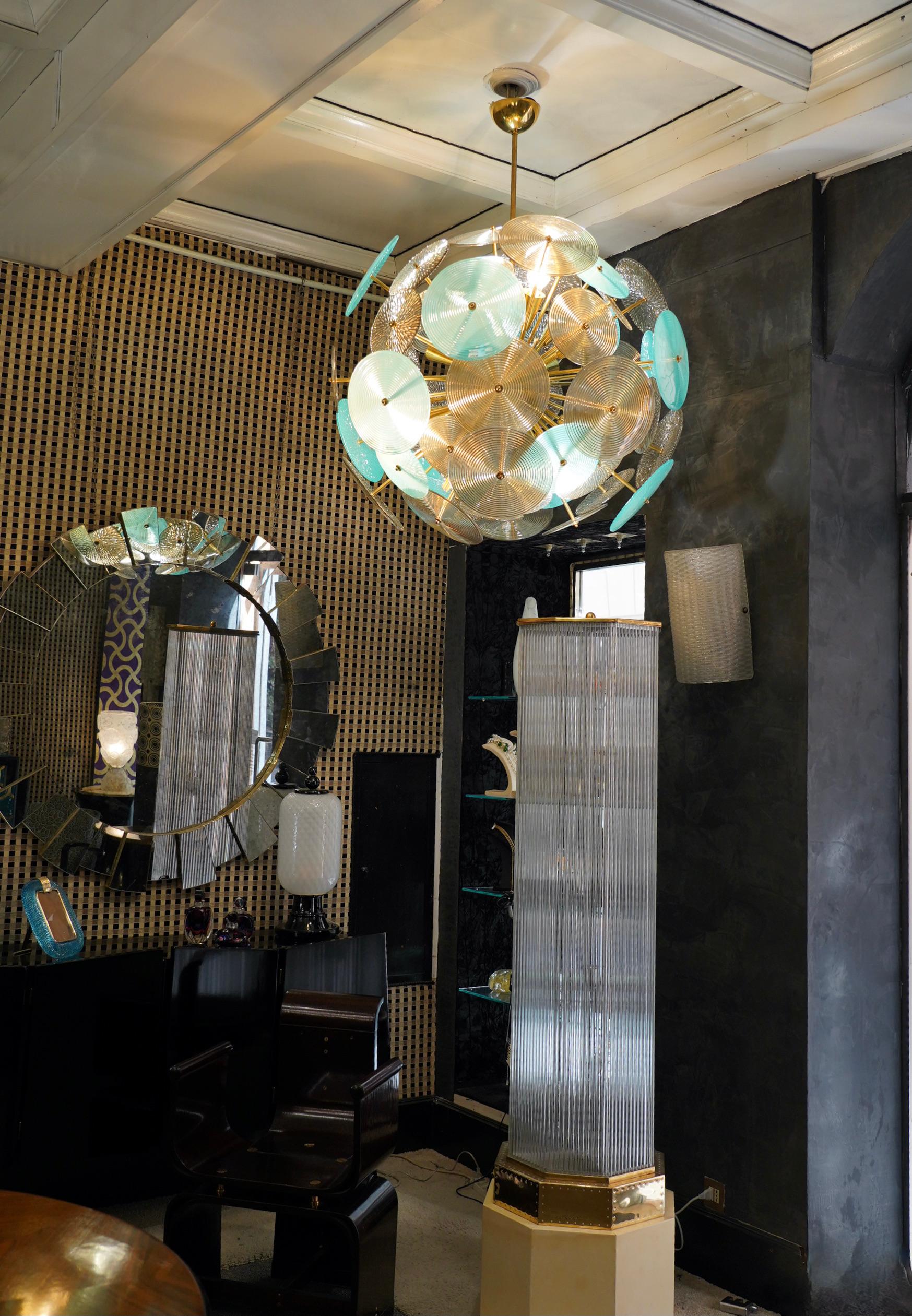 The large turquoise and smoked glass disks make up this Murano chandelier from the 1980. A Classic Sputnik from the middle of the century.

Made of a large central sphere in which brass rods are screwed, glass disks are placed above the brass rods.