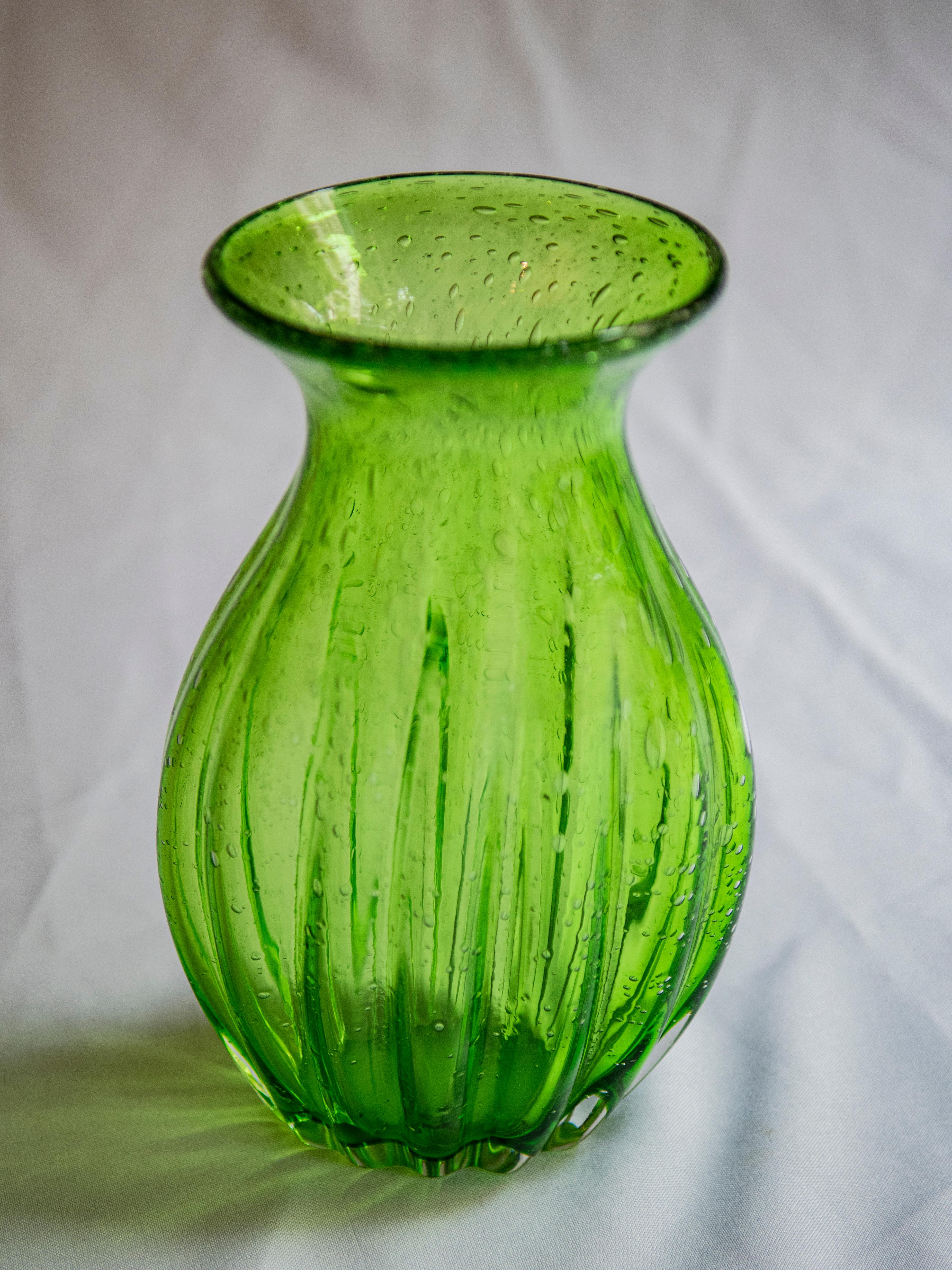 Behold the ethereal beauty of Murano's light green bubbling glass vase—an exquisite fusion of elegance and artistry. Crafted by skilled artisans using traditional Murano glassblowing techniques, this vase captivates with its delicate hue and