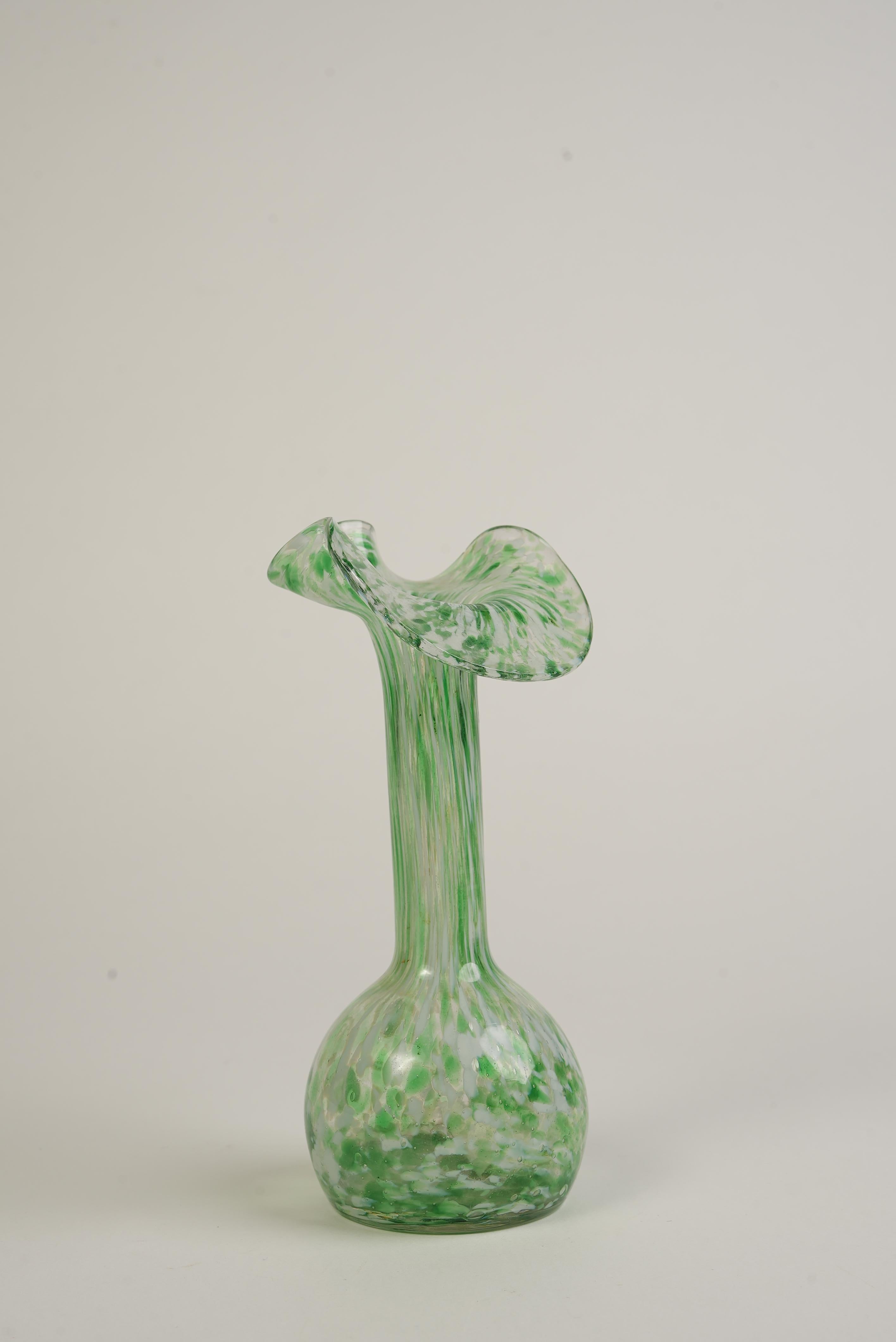 Questo affascinante vaso in stile Murano esemplifica la maestria della tradizionale lavorazione del vetro italiana. Soffiato a mano con notevole maestria, presenta un bordo svasato e arruffato e una base arrotondata, mostrando vivaci motivi