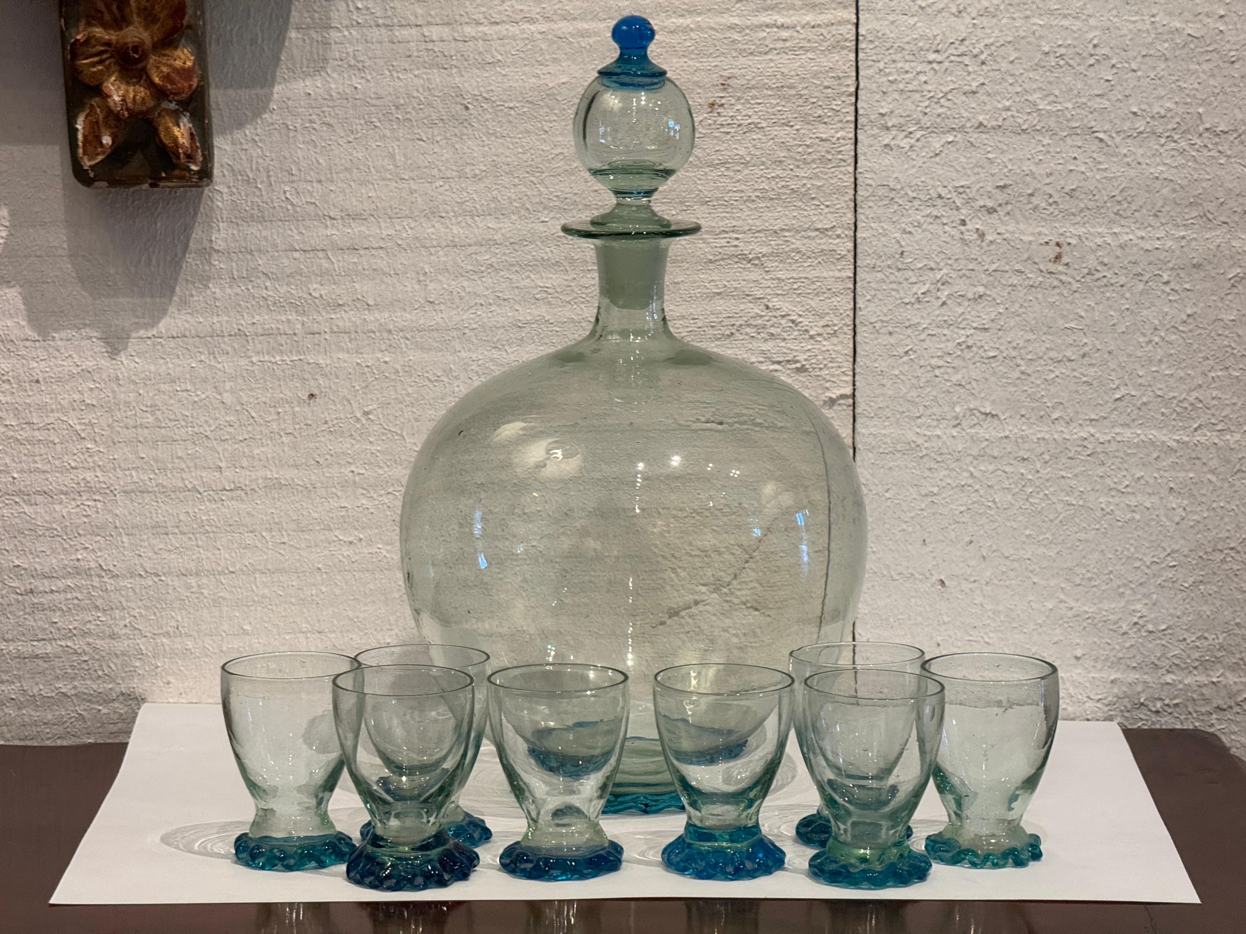 Juego de cristal de Murano que incluye un gran decantador soplado a mano con tapón a juego y ocho copas. Cada pieza presenta las características burbujas de aire y la ligera ondulación del vidrio moldeado a mano, con una característica decoración