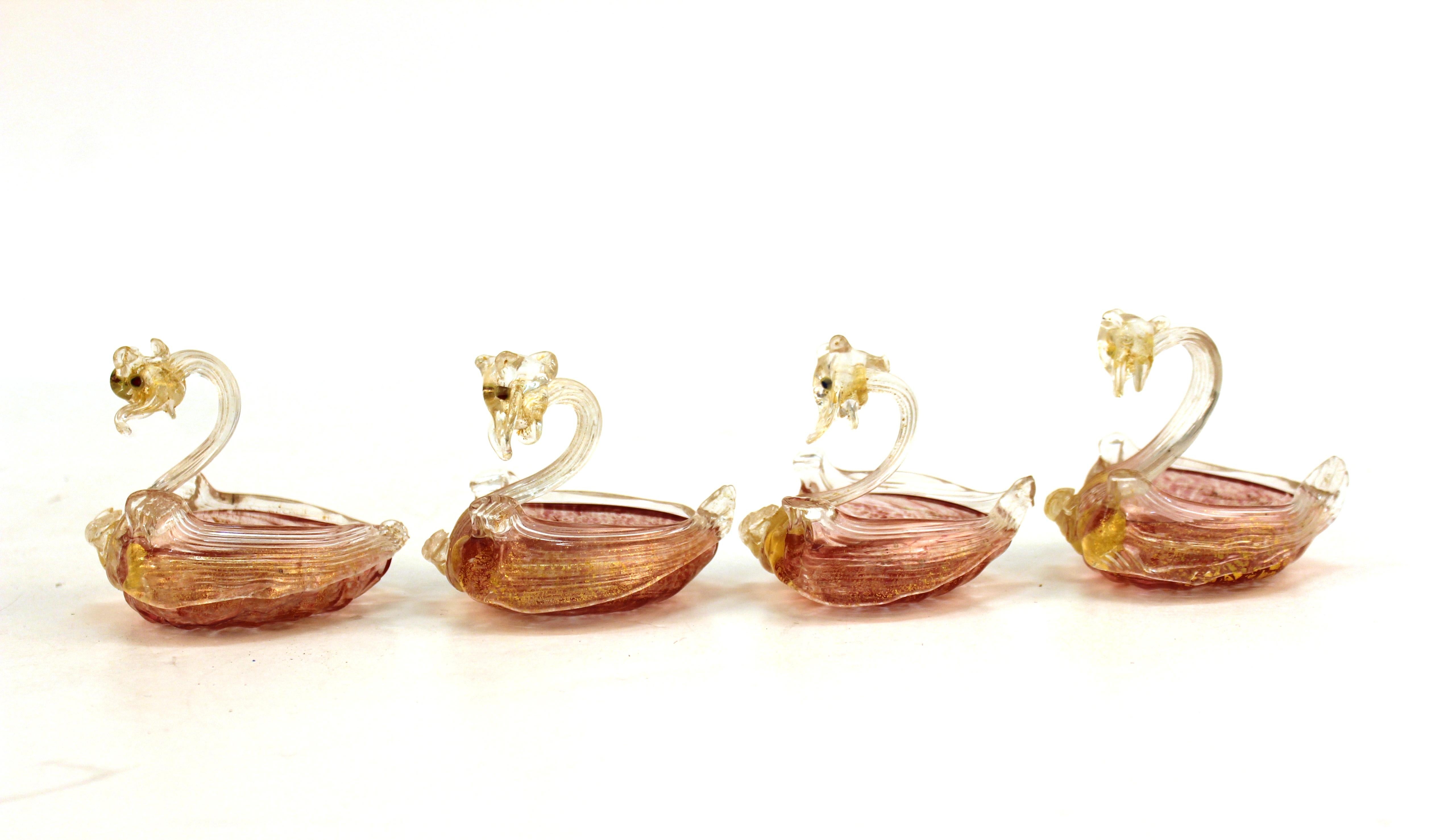 Venetian Murano handblown glass swan-shaped salt cellars attributed to Salviati and made in the 1940s in Italy. The set of four swans have clear and raspberry pink bodies accented with gold leaf. One swan with old repaired breaks. In good vintage