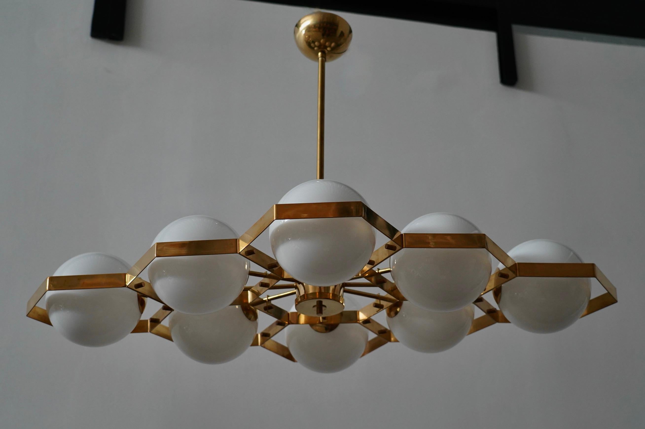 This chandelier stands out for its distinctive rhomboid structure and unique design for the brass spheres. The Murano furnaces create an undeniably timeless design, simple yet elegant.

The chandelier has a polished brass structure composed of a