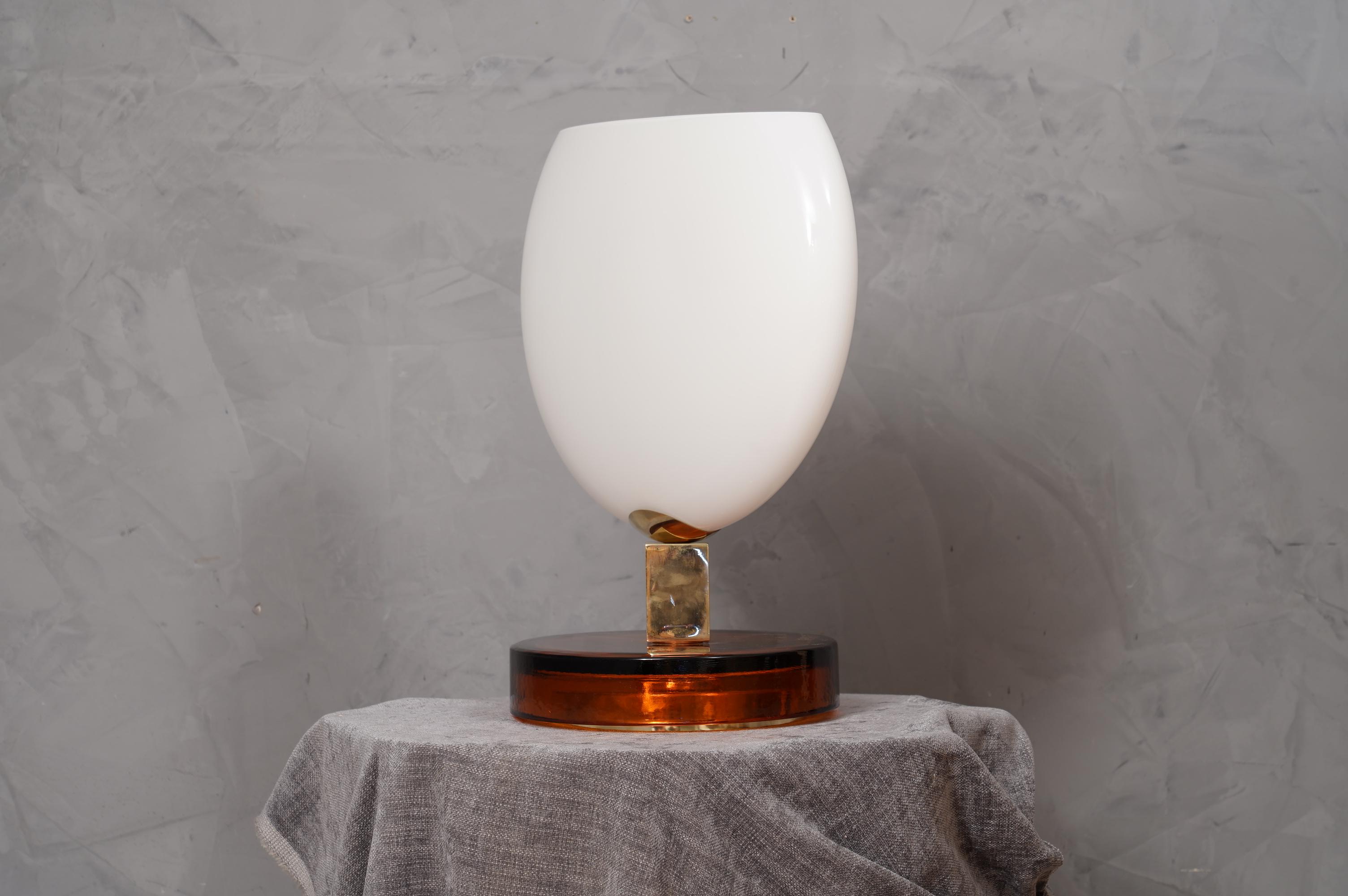 Precious and unique hand-blown Murano white glass, classic but original design with a strong contrast between the white of the glass and the amber of its base lamp.

The lamp is composed of a round base in Murano amber glass, above it is positioned