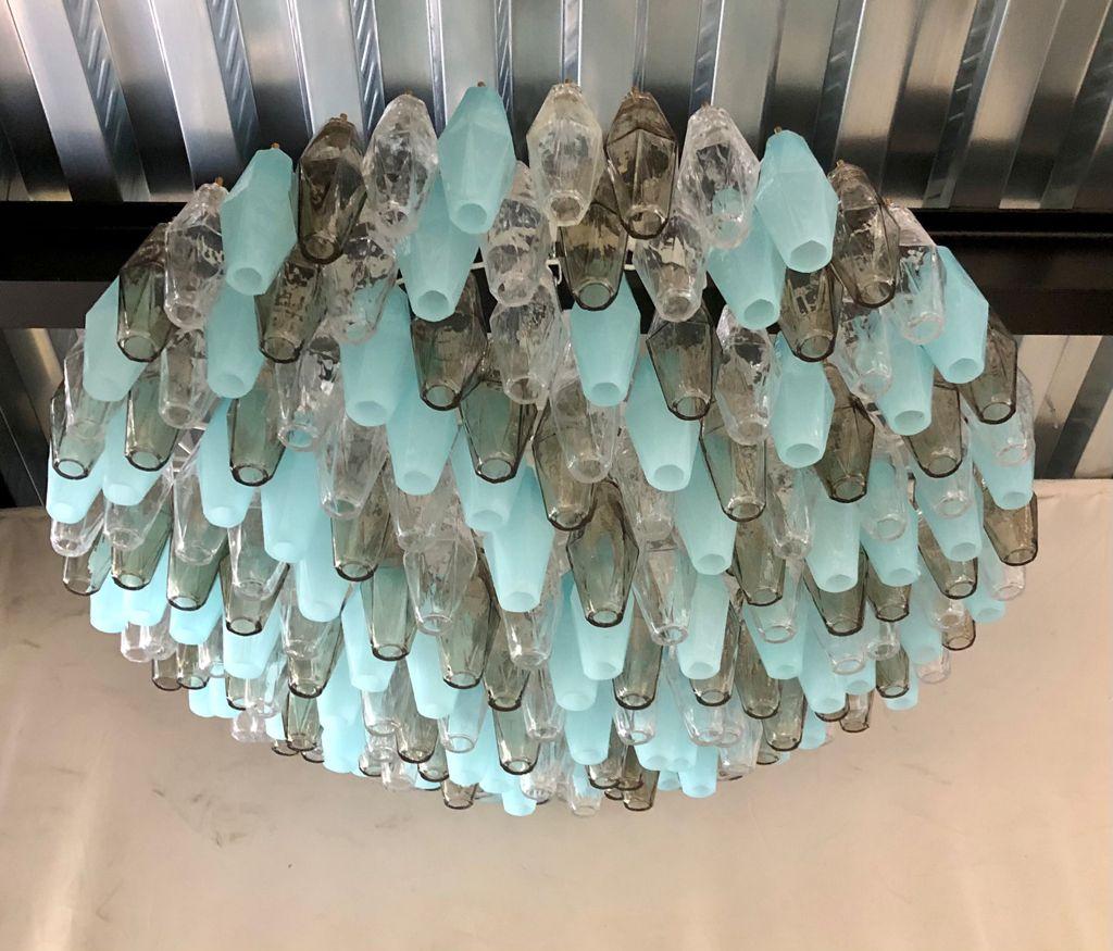 Splendid Murano glass chandelier with a particular 196 polychromy ranging from transparent to smoked and then to opal turquoise color. Its design is also very particular round but flattened in height.

The chandelier has a gray iron structure, with