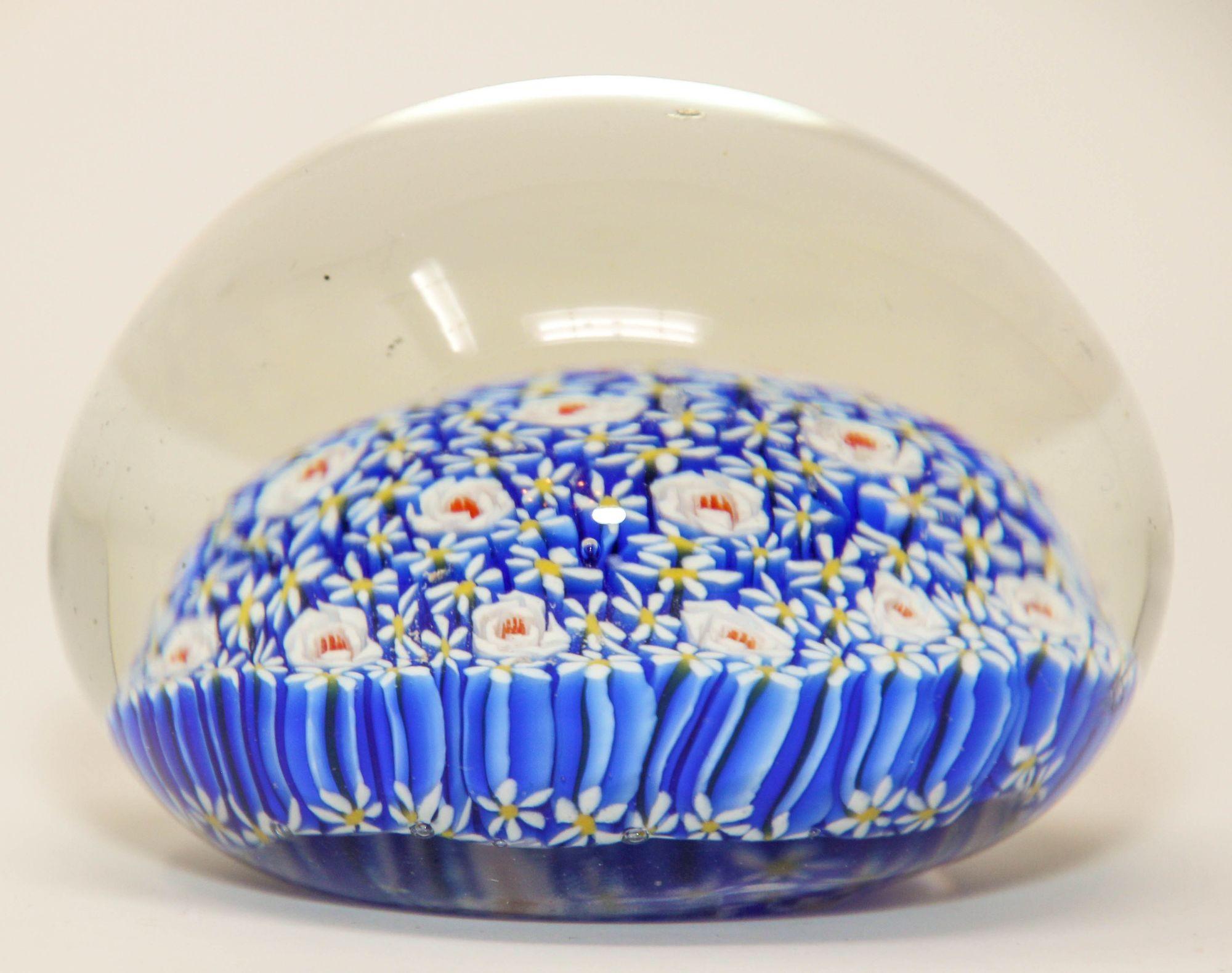 Small vintage Venini Murano glass collectable paper weight.
Beautiful Italian art glass paperweight in millefiori design in various shades of blue, white, with some reds, and yellows in clear case accenting the close concentric complex.
Murano