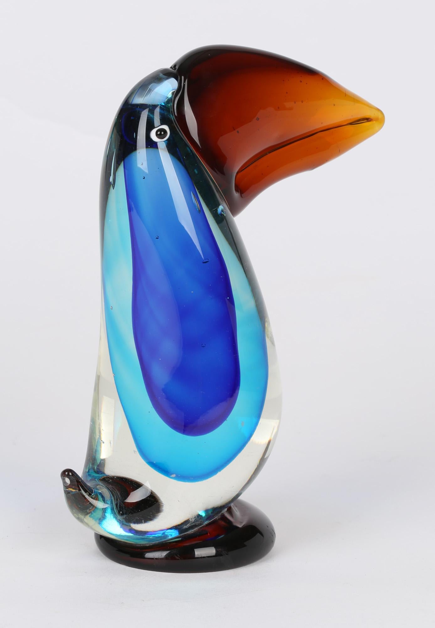 A very stylish Italian Murano art glass figure of a toucan dating from around 1970. The heavily made solid blown glass figure stands on a small rounded amber glass base the body containing blue sommerso coloured glass within clear glass with a small