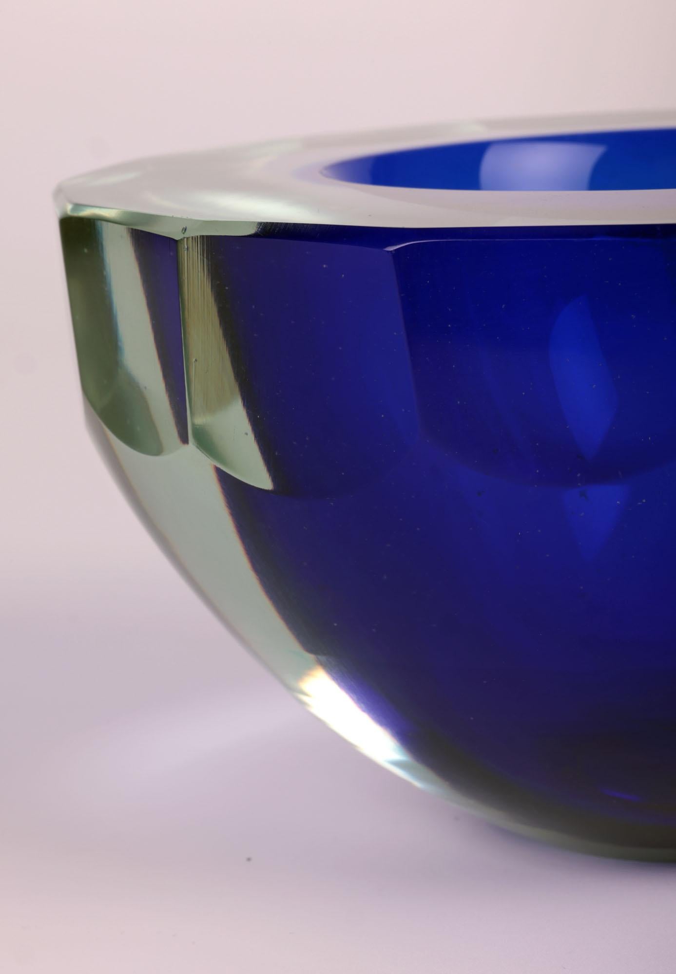 A sculptural and large hand-made Italian blue Sommerso style art glass bowl made on Murano and dating from around 1960. The heavy and thickly made bowl stands on a narrow flat polished round base and is made in a thick yellow/green tinted glass with