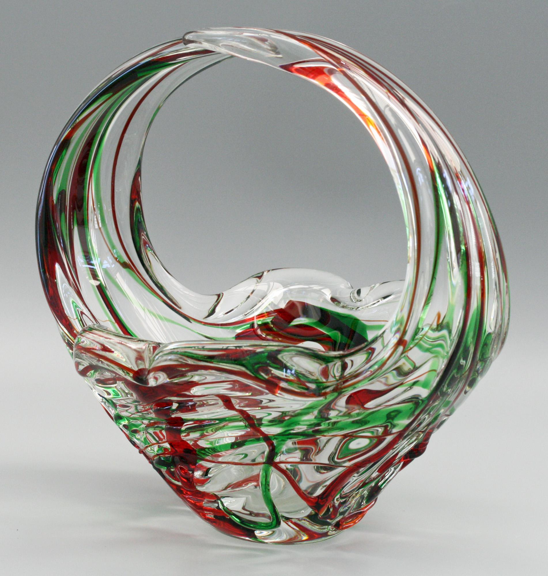 Un bol en forme de panier en verre d'art italien de Murano très frappant et élégant avec des traînées rouges et vertes datant du milieu du 20e siècle. Le bol est fortement moulé en verre transparent, avec une base en forme de fleur et deux poignées