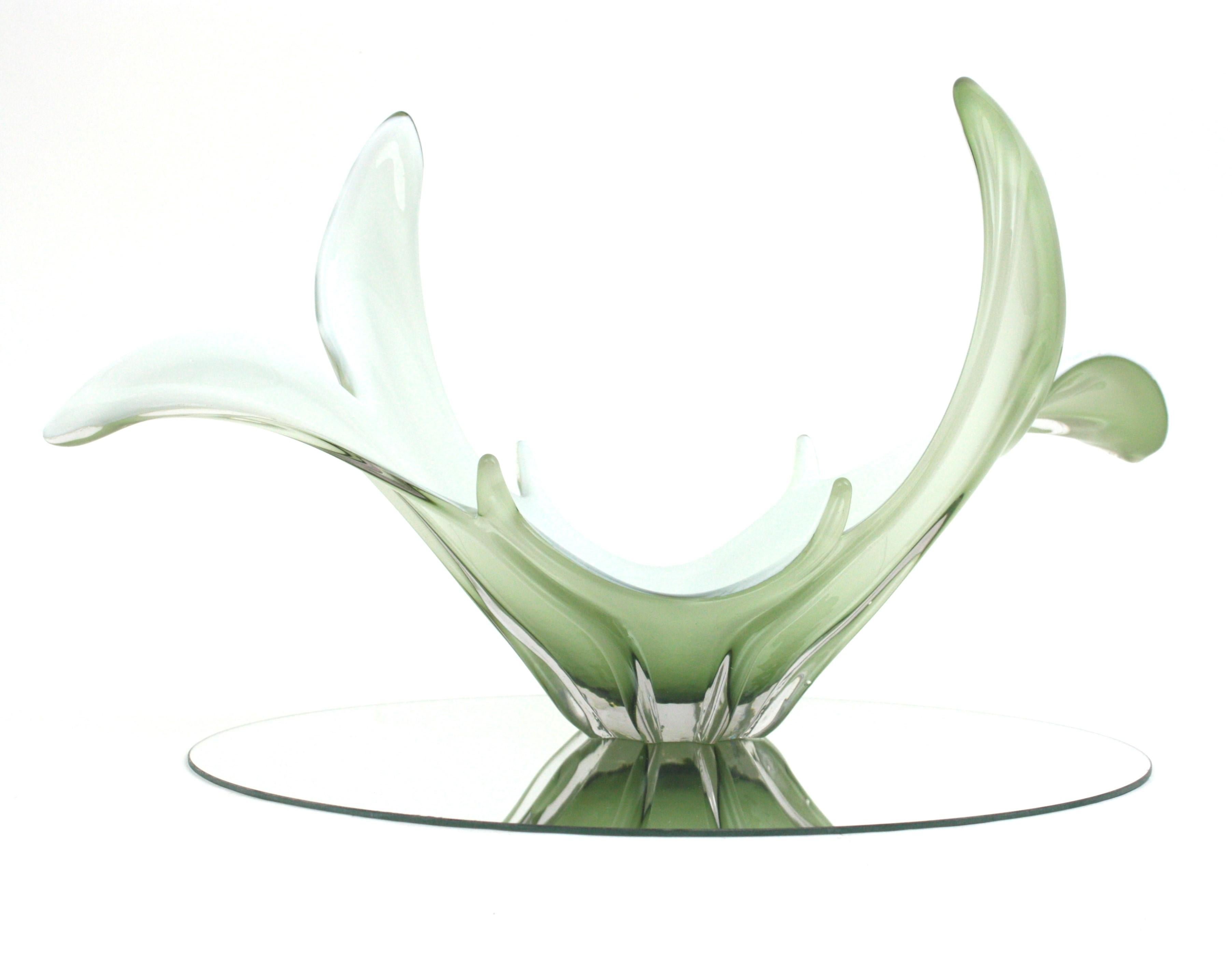 Centre de table / vase en verre de Murano soufflé à la main, vert pâle et blanc, très décoratif, avec un design organique. Italie, années 1960
Verre vert pâle encastré dans du verre transparent. La partie intérieure est en verre opalin blanc.
Il